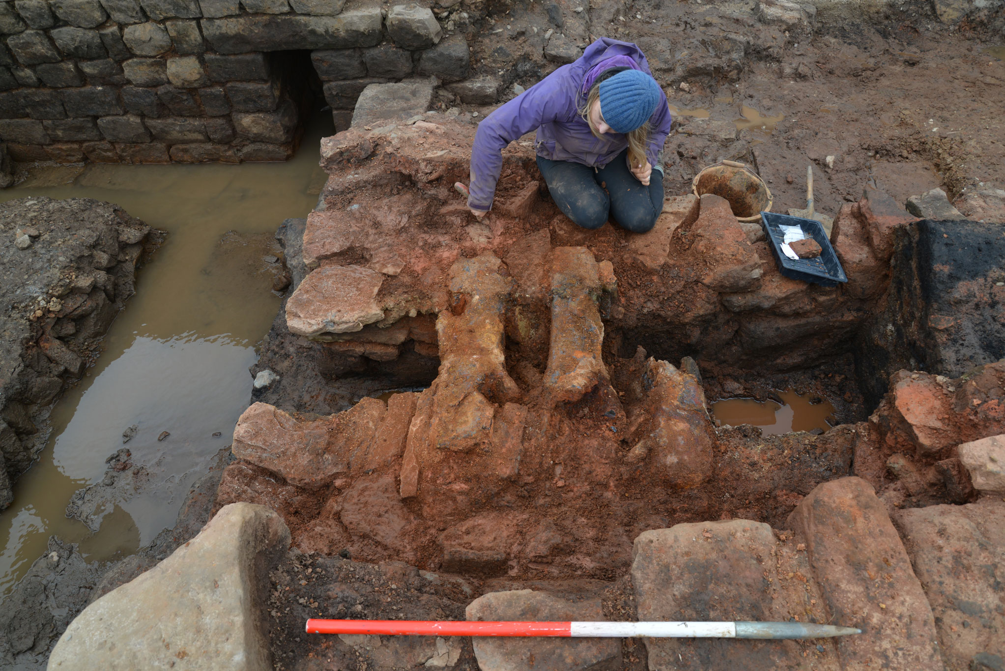 A female archaeologist excavating a flue within a bathhouse.