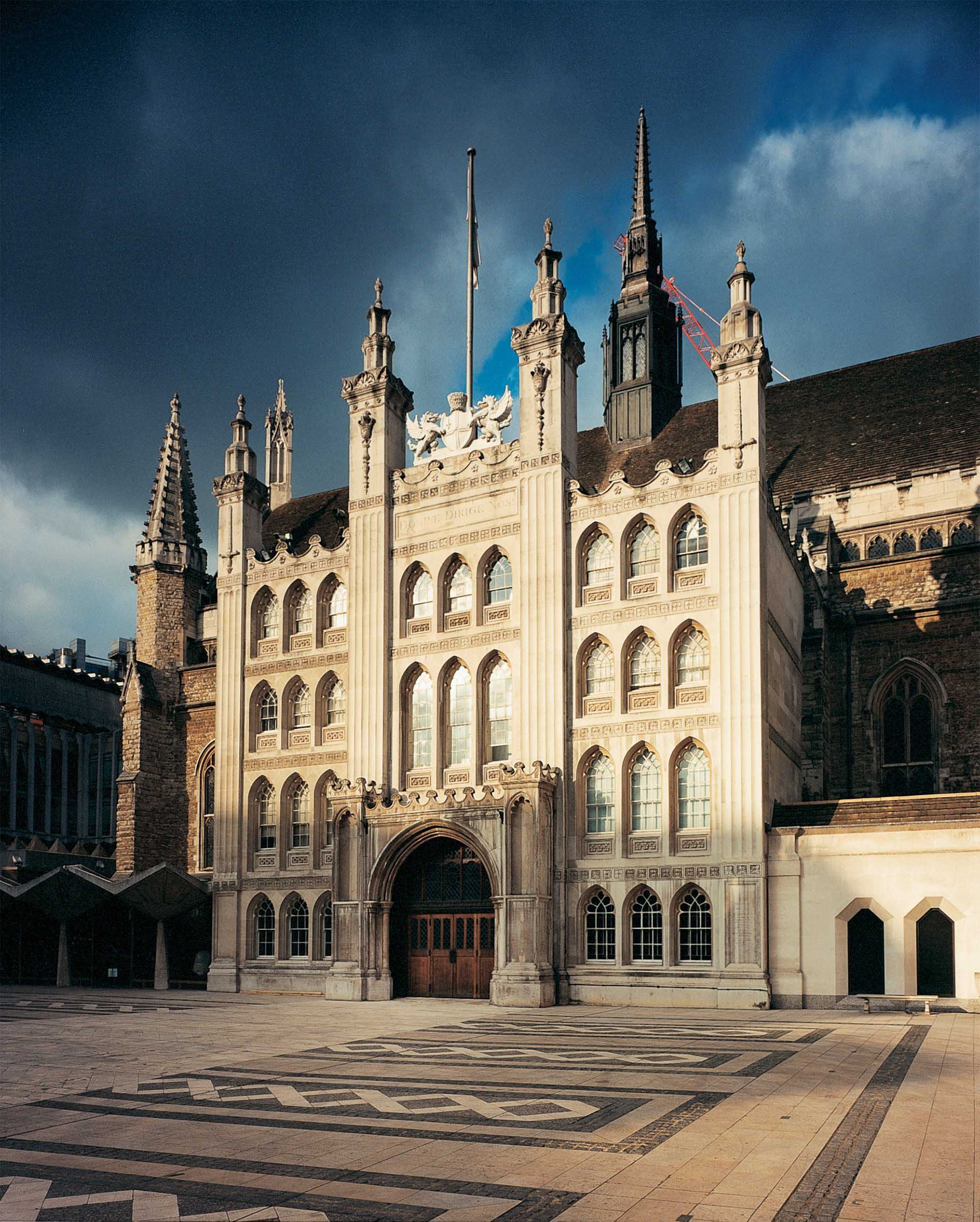 Front of large medieval town hall with turrets.