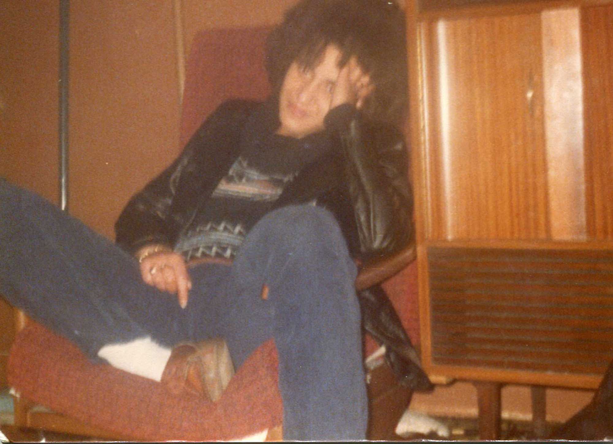 Linda Brognan as a young woman lounges on a chair with her head resting on her hand.