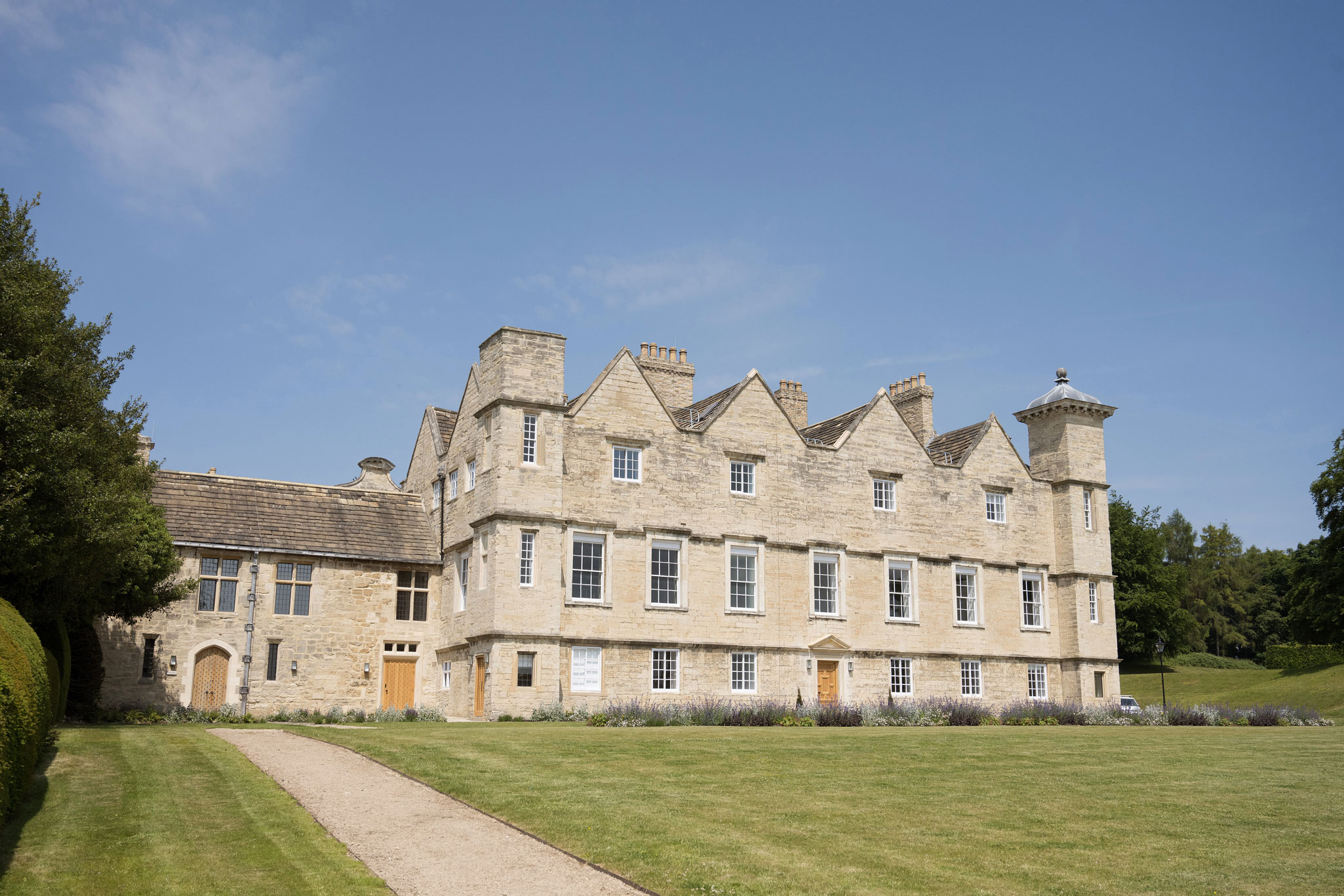 A general view of a country house with a three storey range and adjacent two storey element, constructed of stone, showing results of restoration.