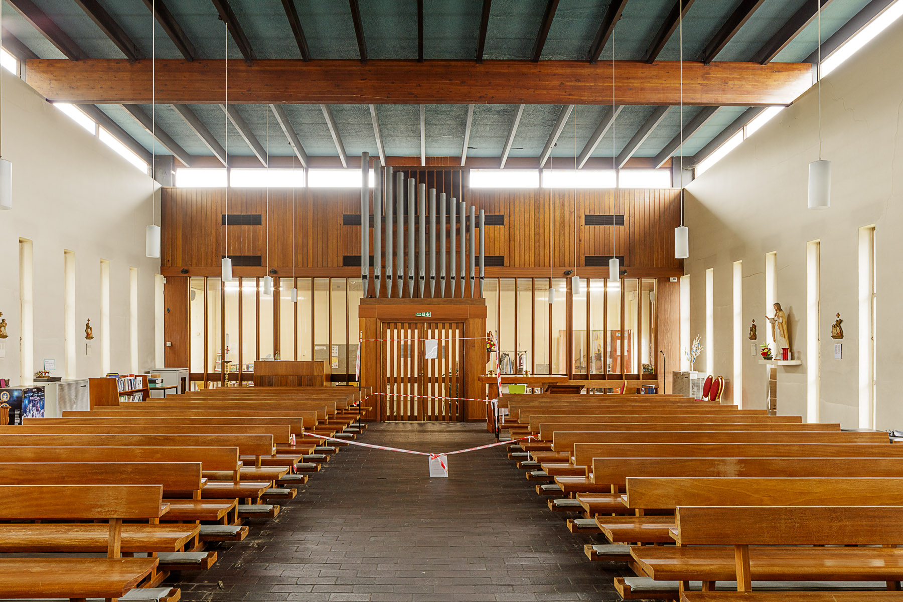 Interior of church looking down the central aisle towards the exit door and organ pipes above it.