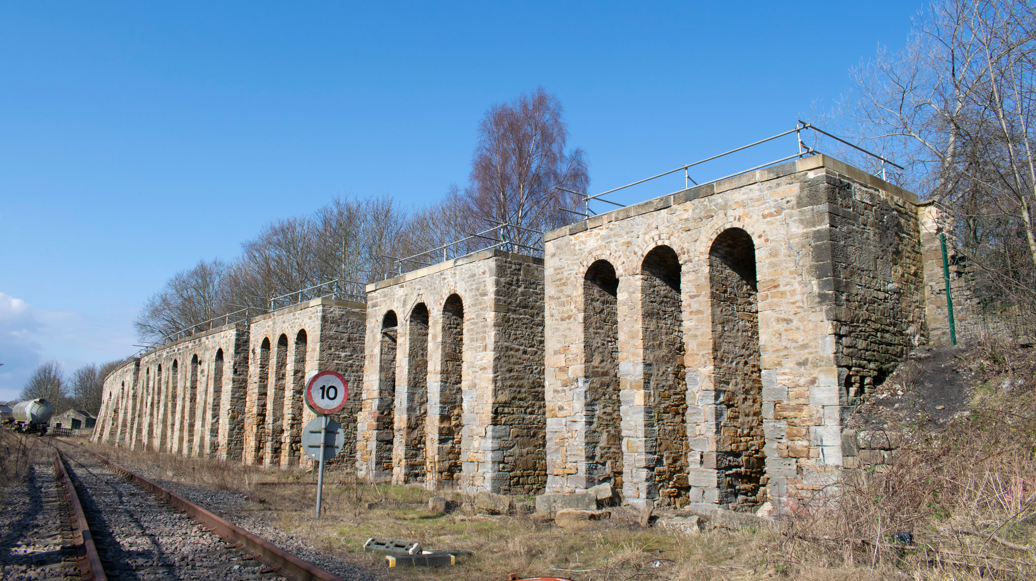 The stone arches of  a coal drop structure next to a railway line.