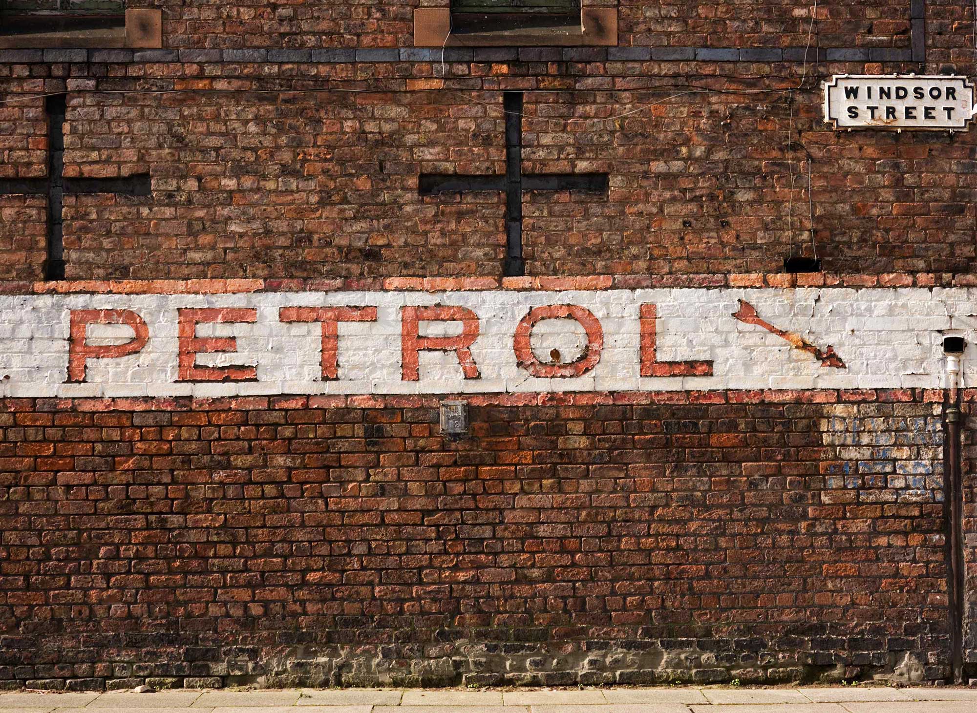 Image of a white and red sign reading 'petrol' on the front of a brick building.