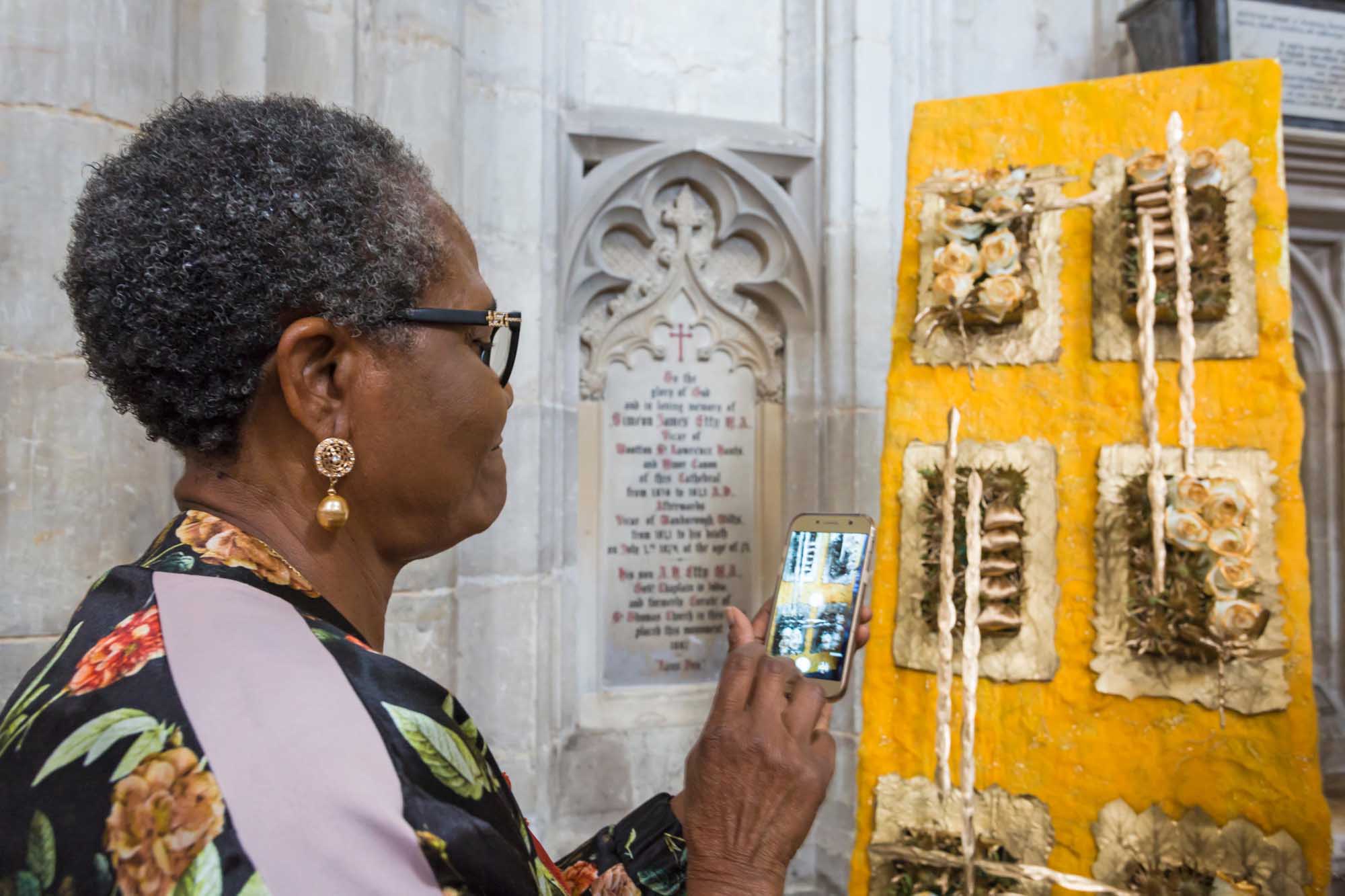 A woman taking a photo of an exhibit with her phone