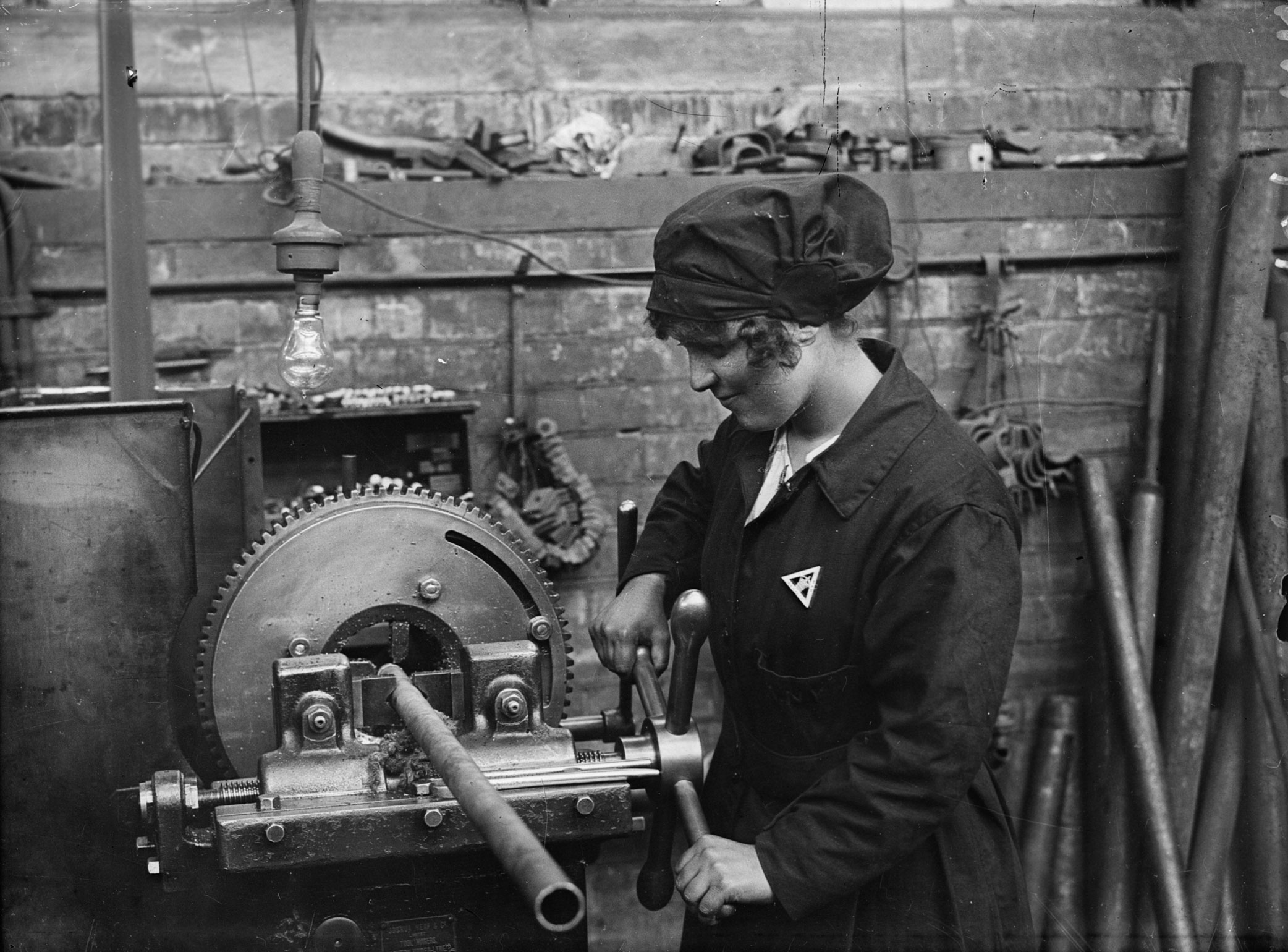 A black and white archive image showing a First World War era woman worker operating a machine.