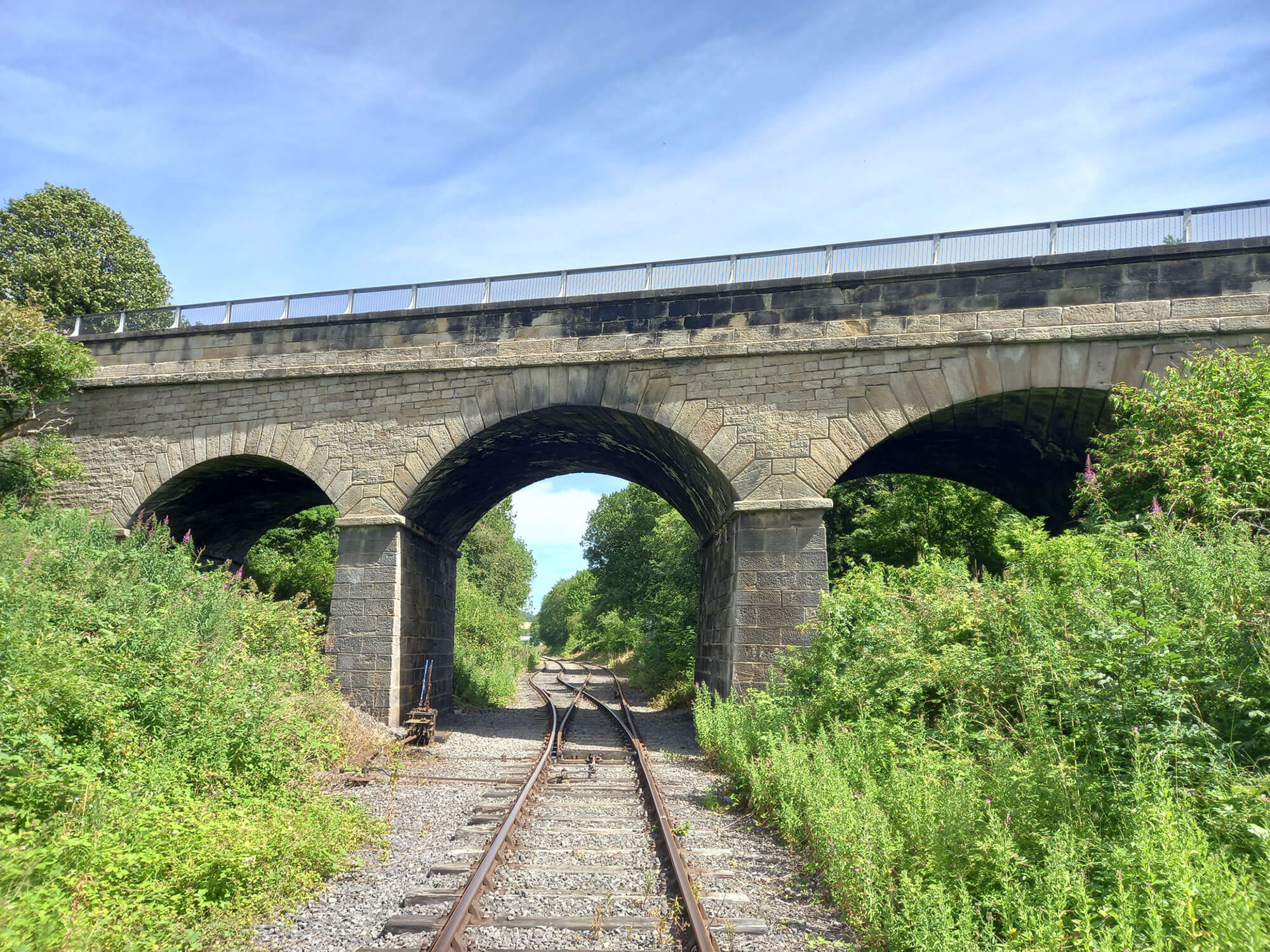 Alt text: a large stone bridge spanning a railway line.