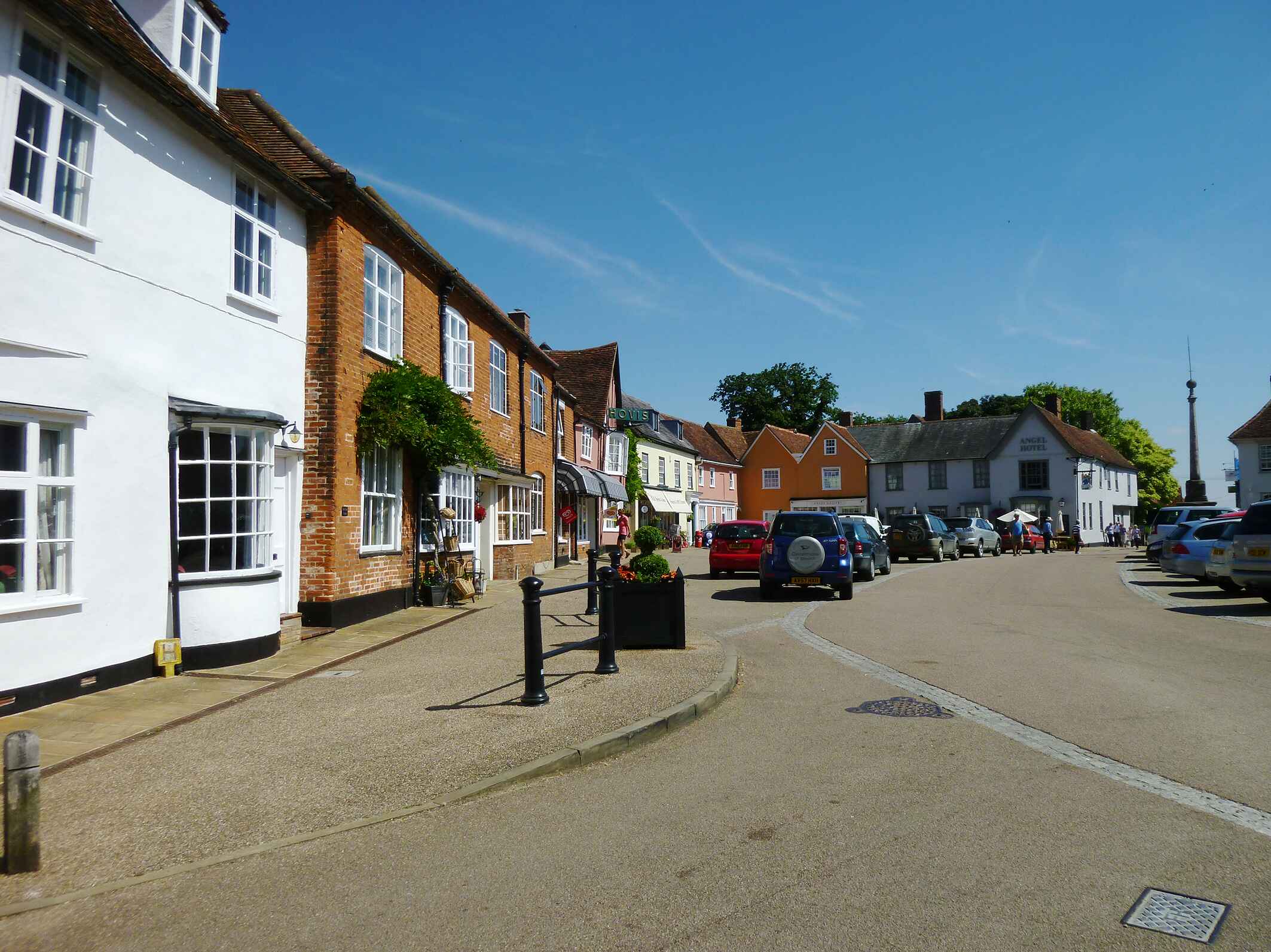 Road with houses and shops with parked cars outside