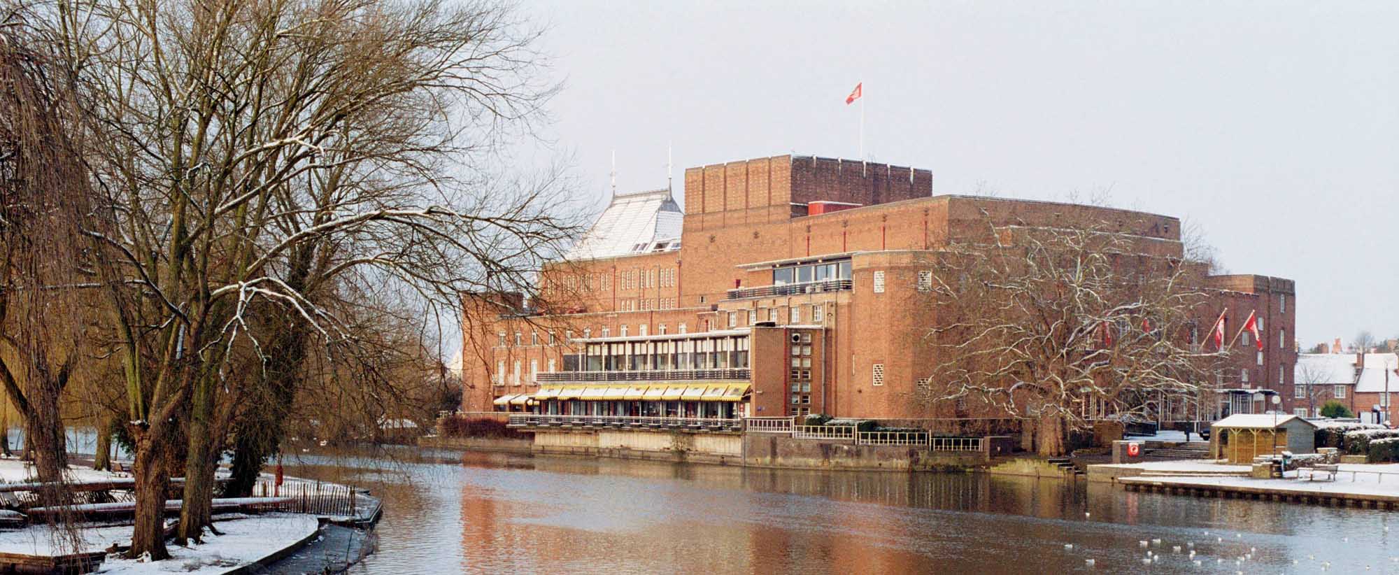 A photograph of the Shakespeare Memorial Centre building in winter, with a river and snow on bare trees in the foreground.