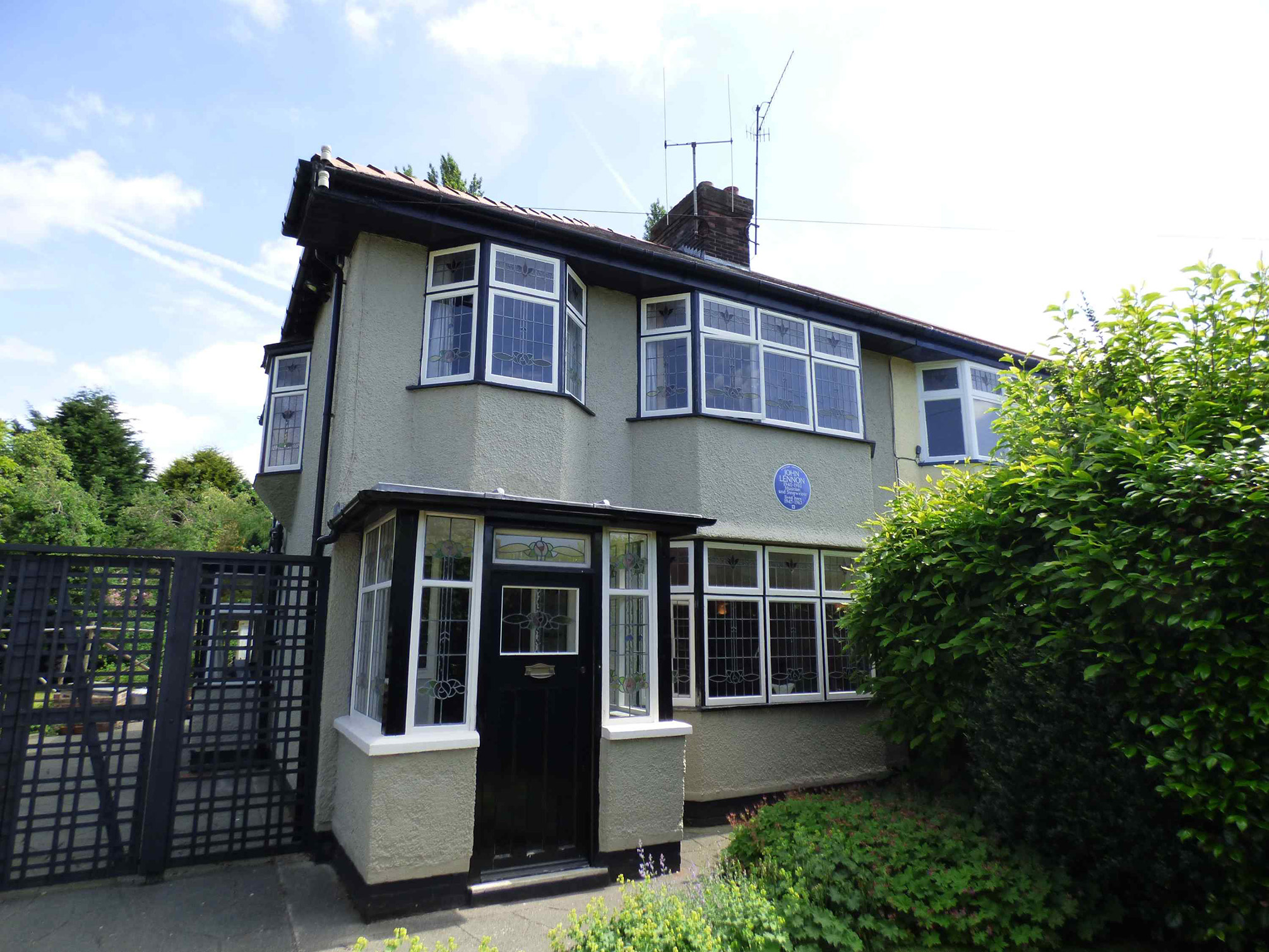 The front exterior of a semi-detached house in Liverpool with a Blue Plaque celebrating the singer, songwriter, musician and peace activist John Lennon