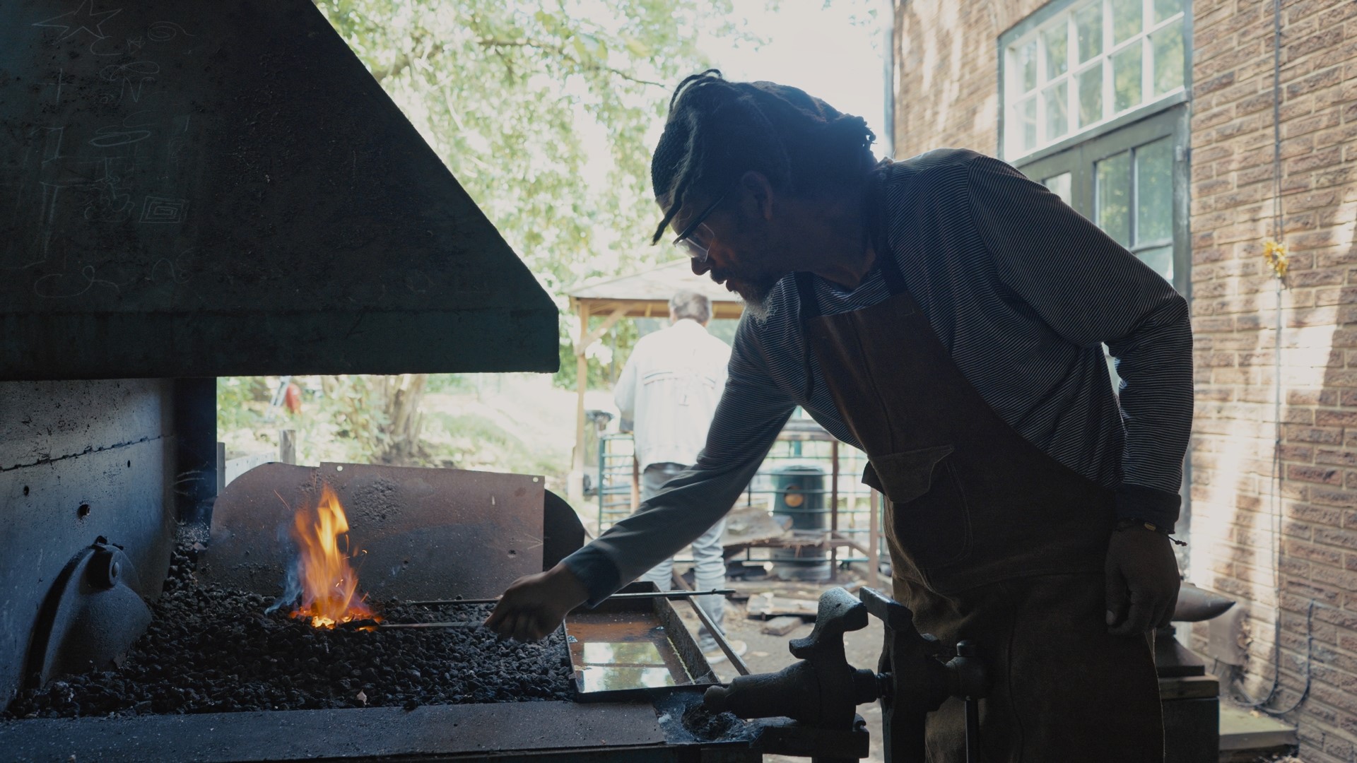 A man holding a piece of metal in hot coals.