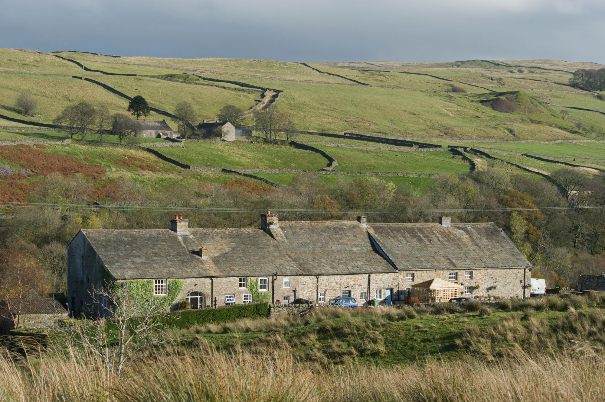 A row of stone cottages with moorland in the foreground and background.