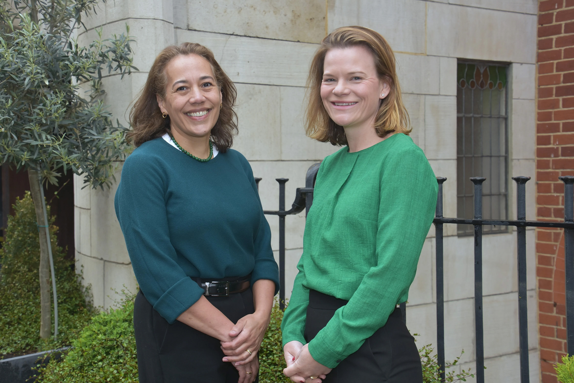 Two ladies standing next to each other outside a building. 