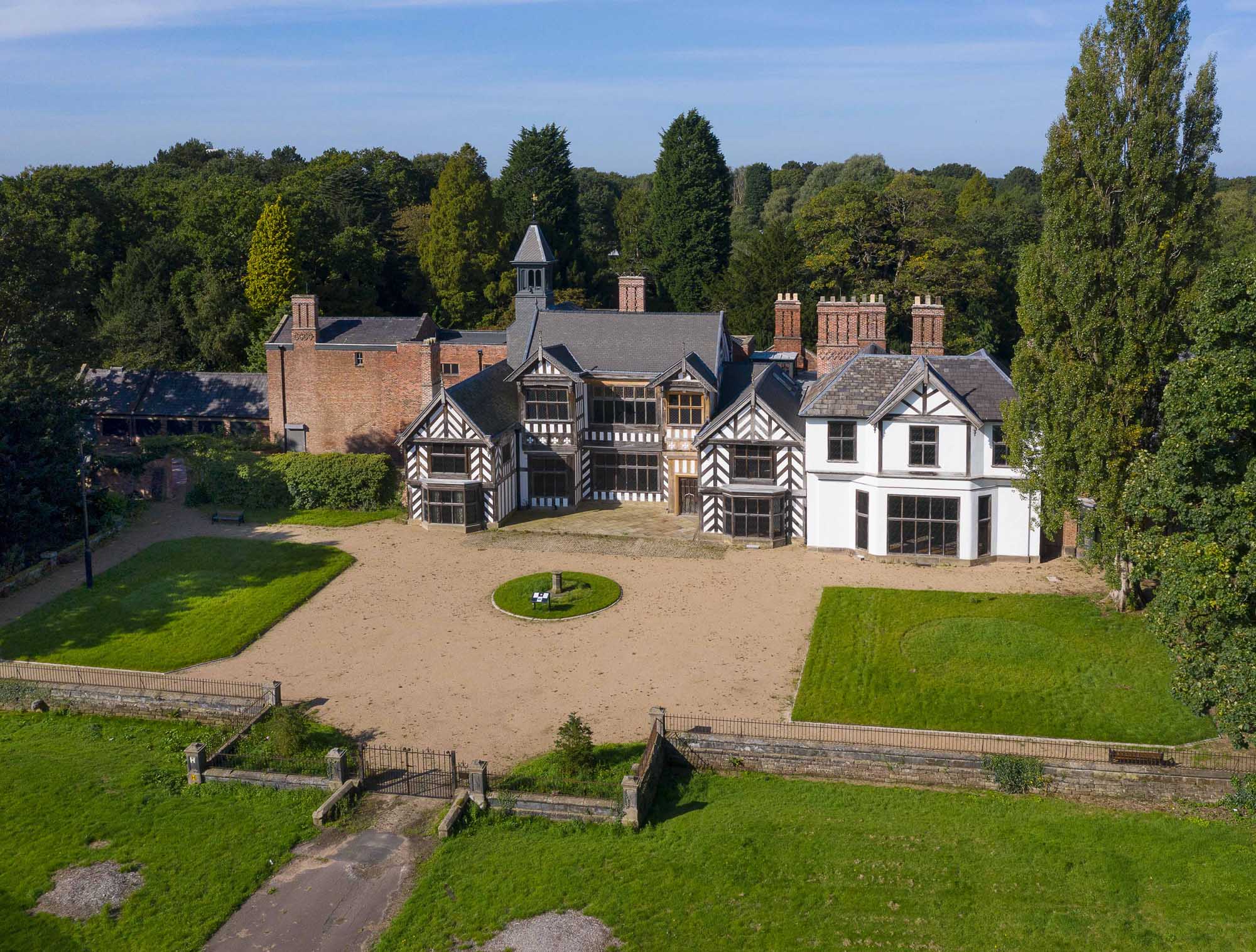 Exterior, east elevation, drone image showing hall after conservation/ restoration work following the arson attack in March 2016. View from east. 16th century stately home with lawns and gravel in foreground. Woods in background.