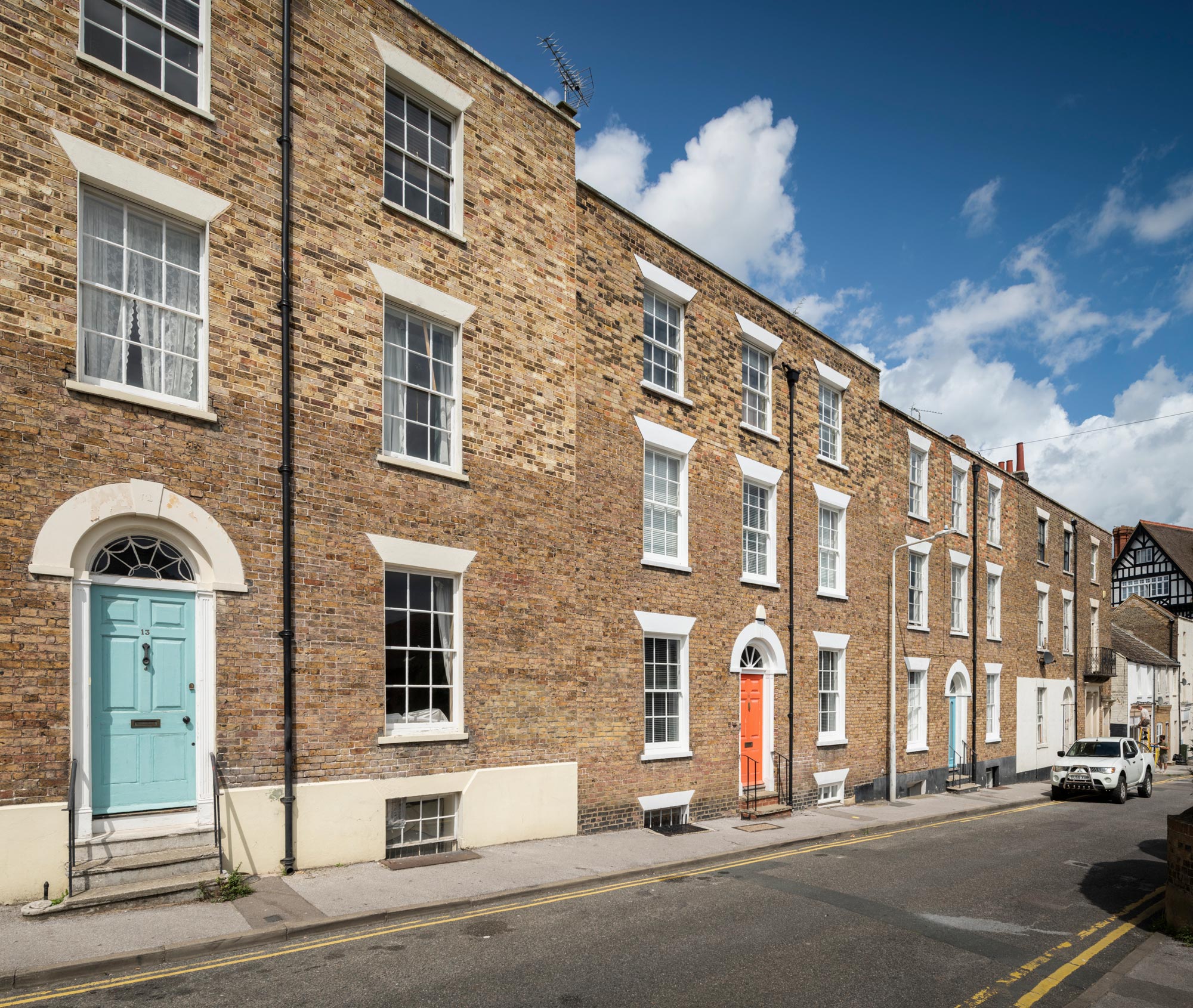 View along a street of three-storey terraced brick houses.