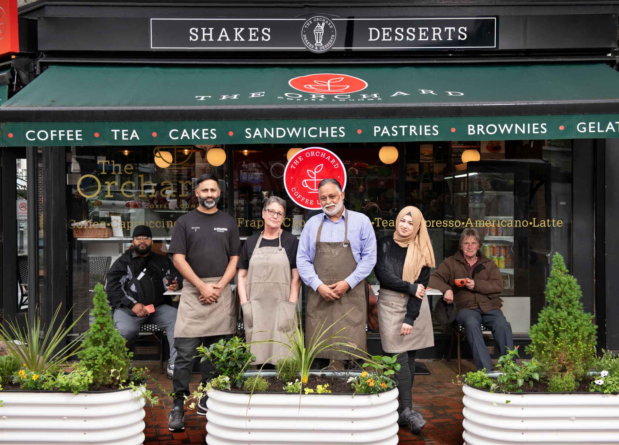 A portrait of shop owners, staff and customers with planted raised beds, part of Greening The Street project.