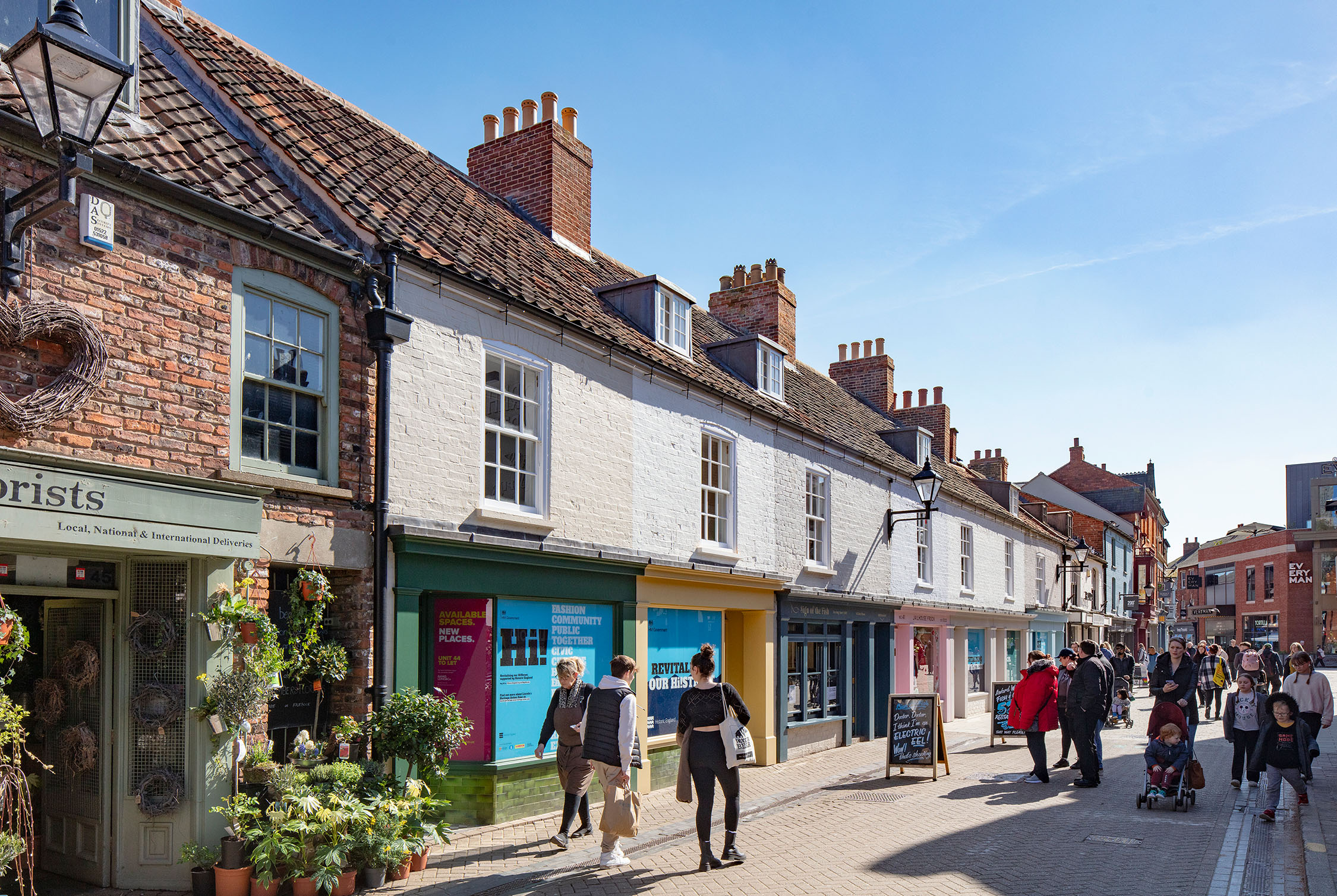 An urban street scene of people and shops on a high street in Lincoln, UK.