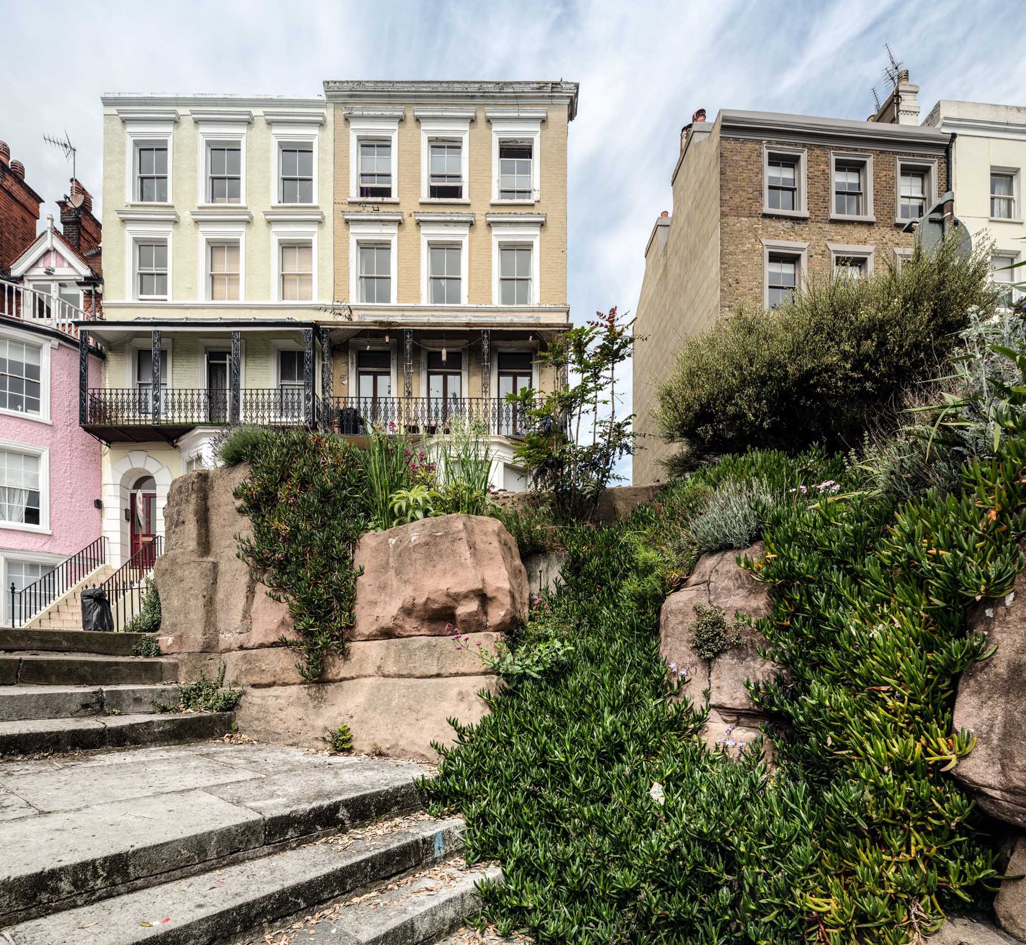 Tall town houses on a cliff setting with artifical rockwork and steps in the foreground.