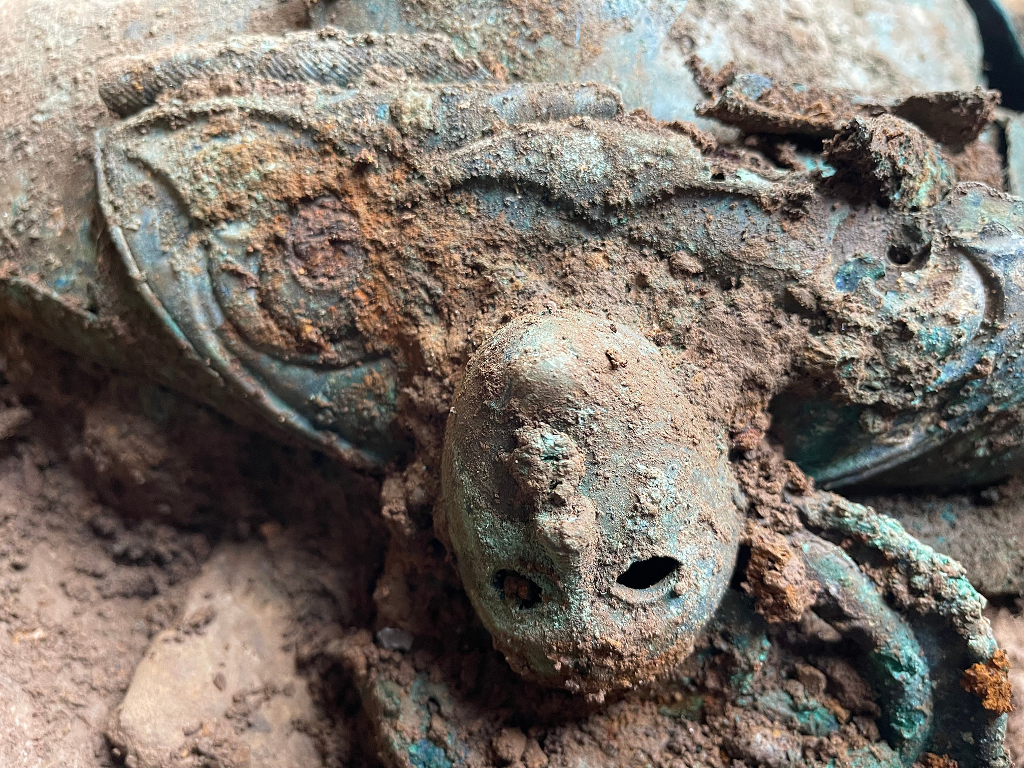 Close up image of an upside down blue face on the edge of a round object, the piece is lying on the ground.