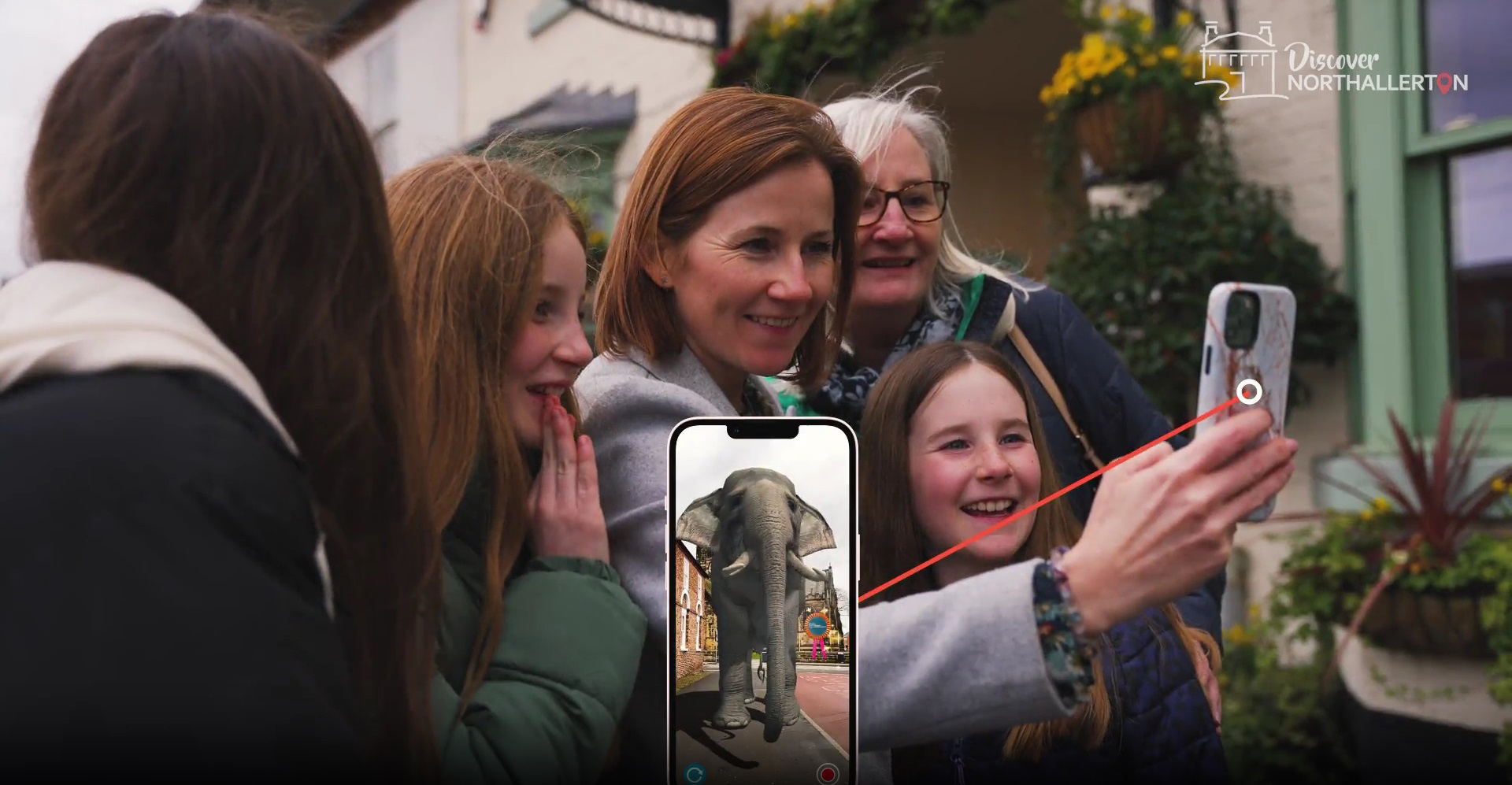 A family group around to look at a phone screen, held up by the mother.