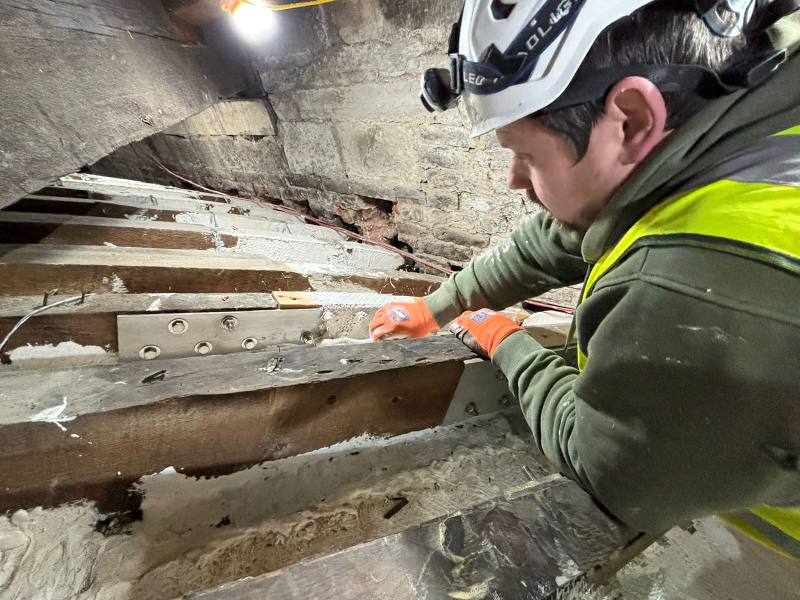 A person working on rafters in the roof space.