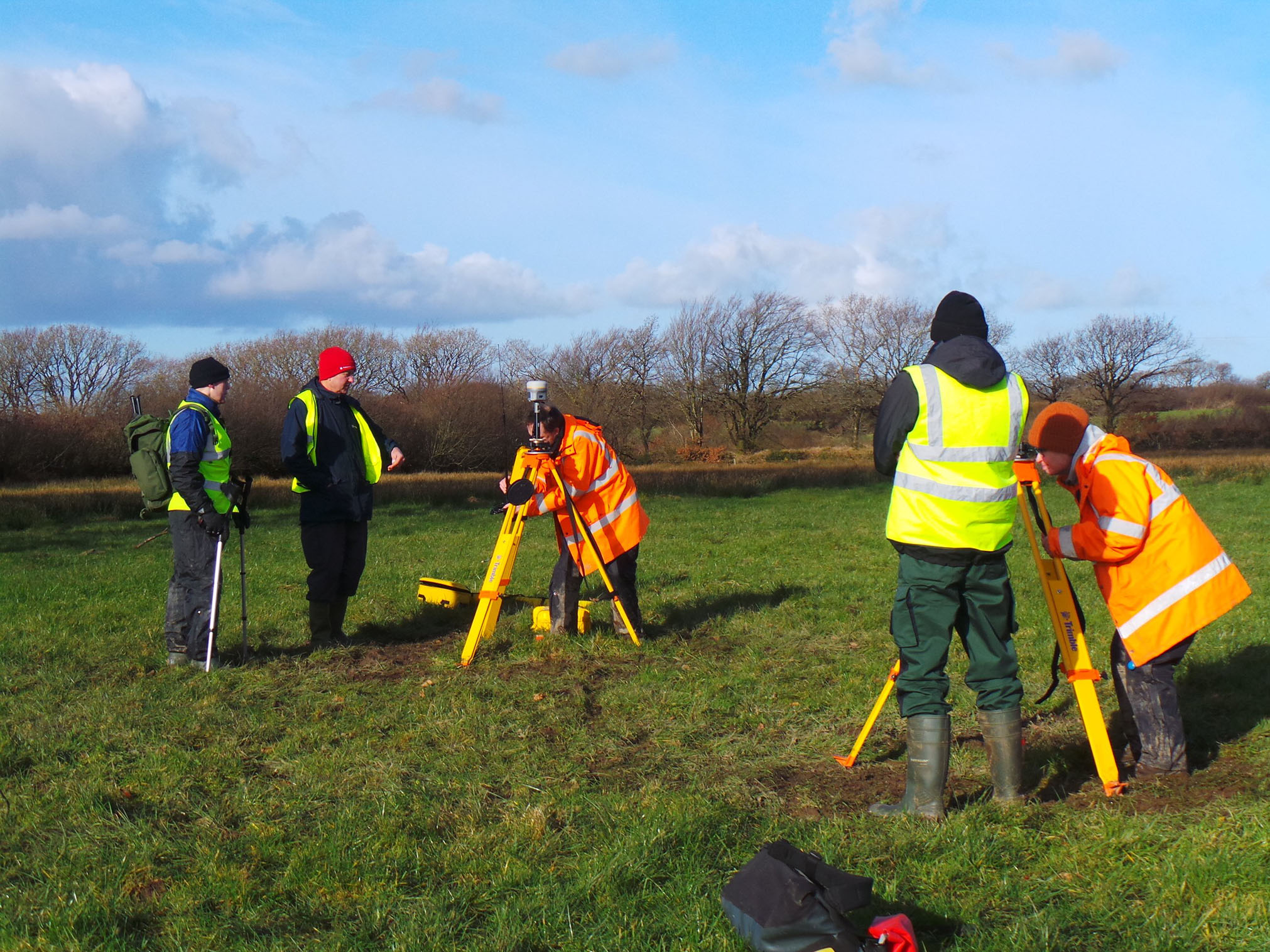 A photograph of a group of people carrying out archaeological survey in a field