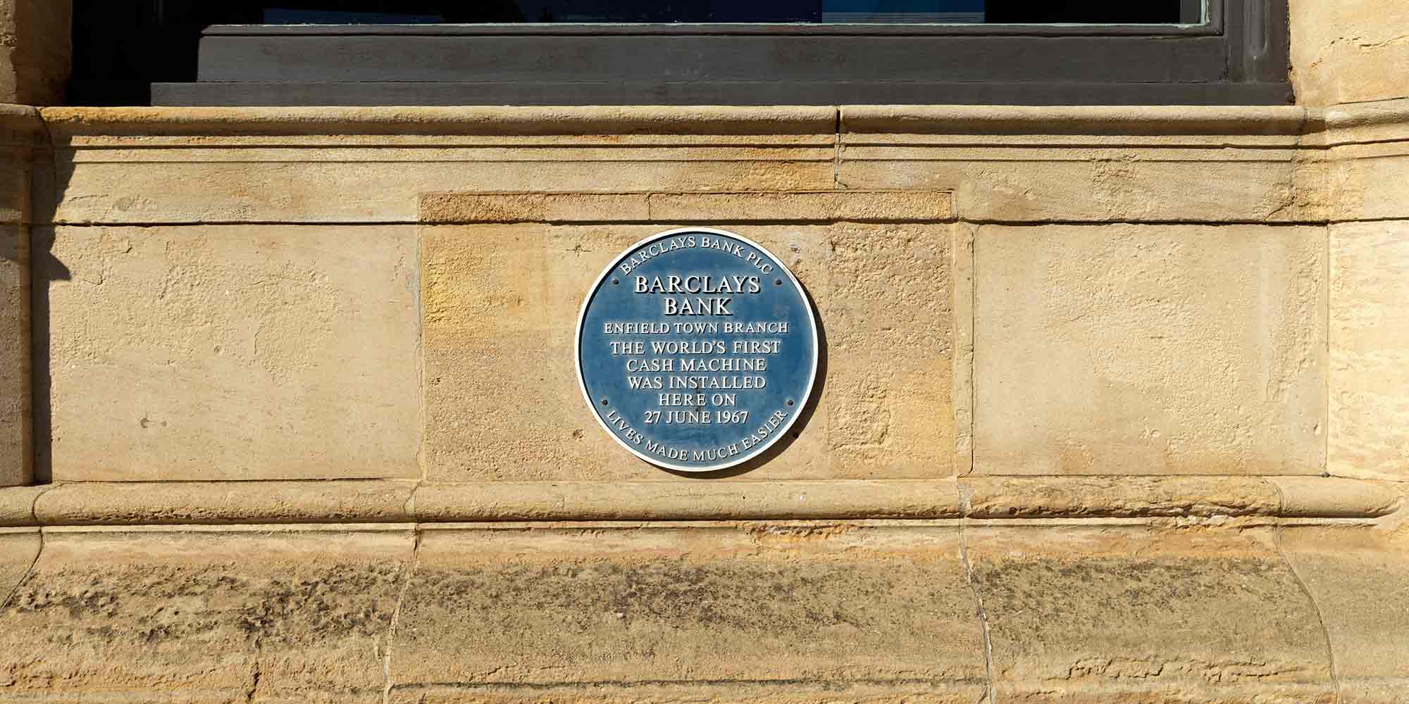 Blue plaque mounted on a stone wall. It reads Barclays Bank, Enfield Town Branch, the world's first cash machine was installed here on 27 June 1967. Lives made much easier.