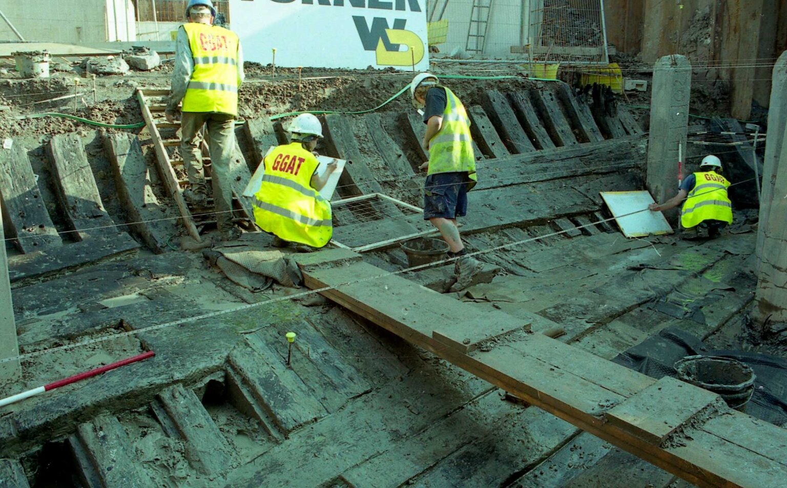 People examine the remains of a wooden ship.