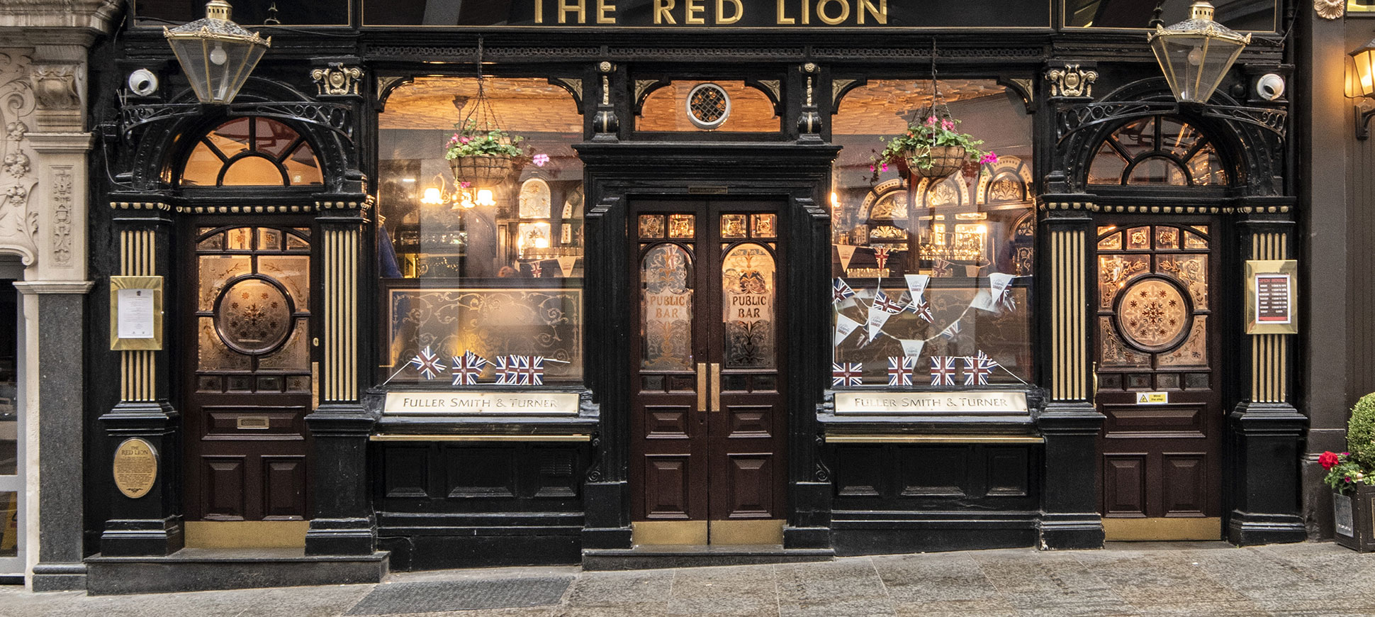 A symmetrical urban pub front with the words "The Red Lion" over the door. 