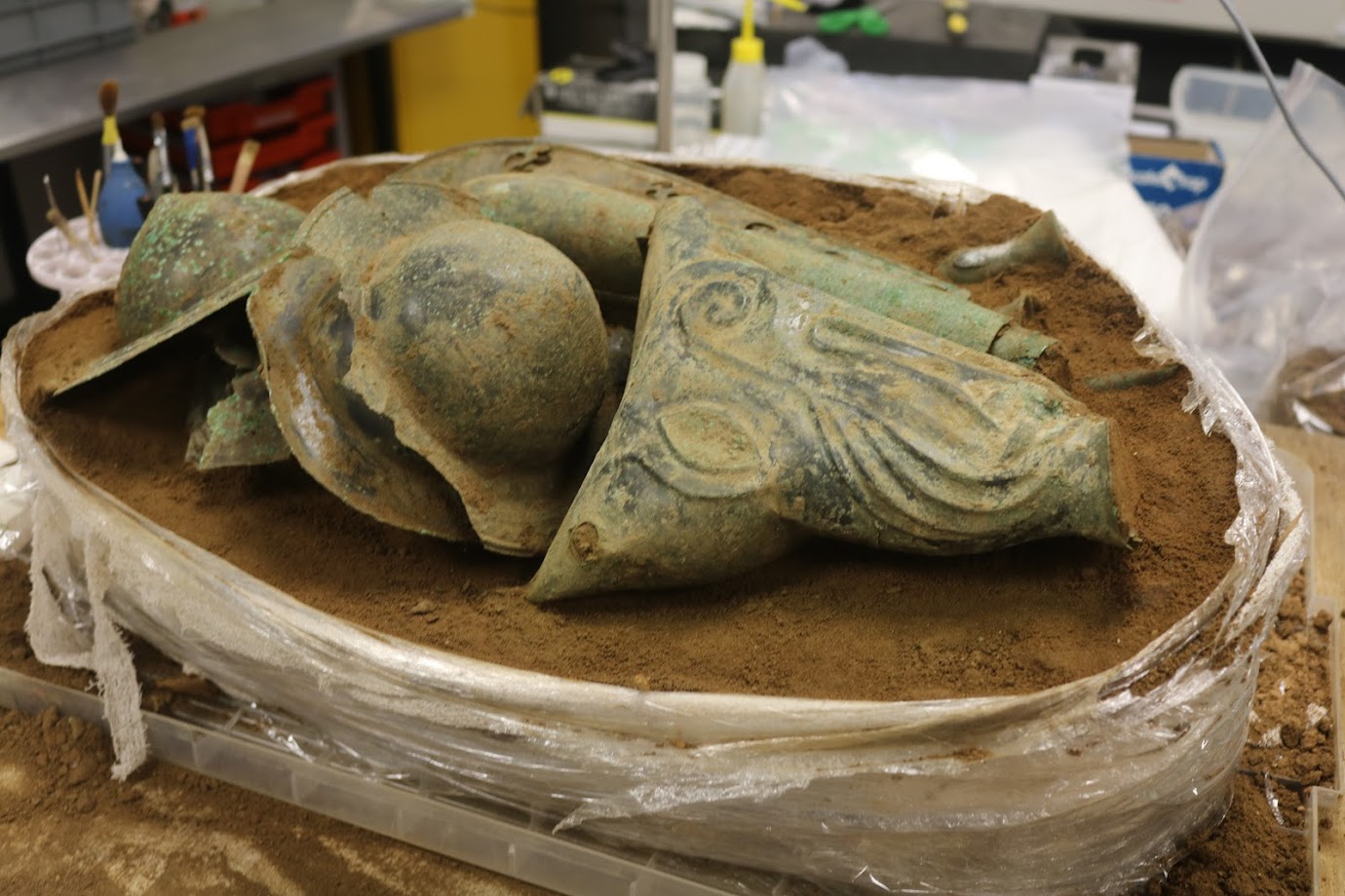 A number of bronze items emerge from a soil block