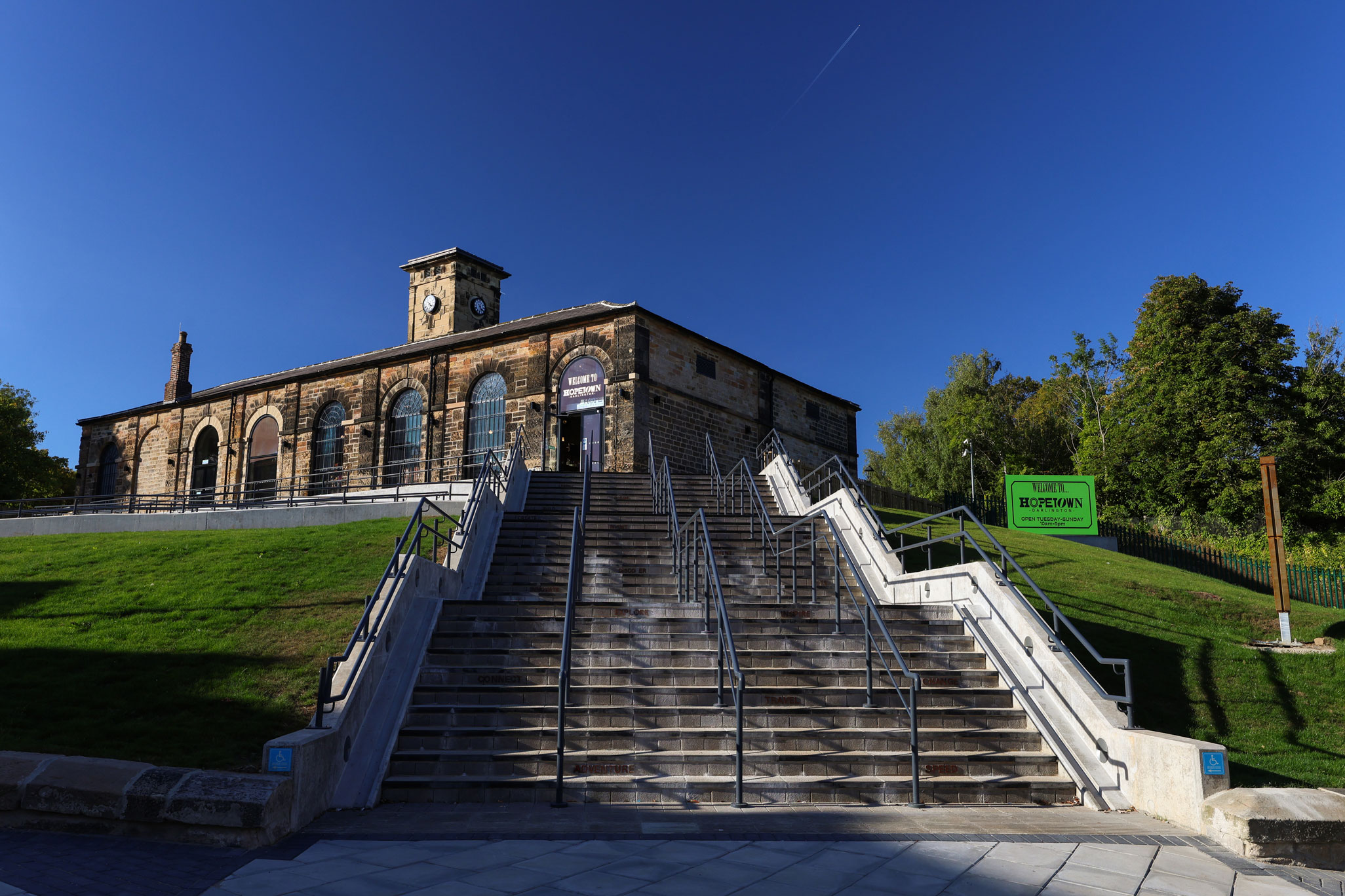 A restored goods depot with a flight of steps and visitor signage in the foreground.