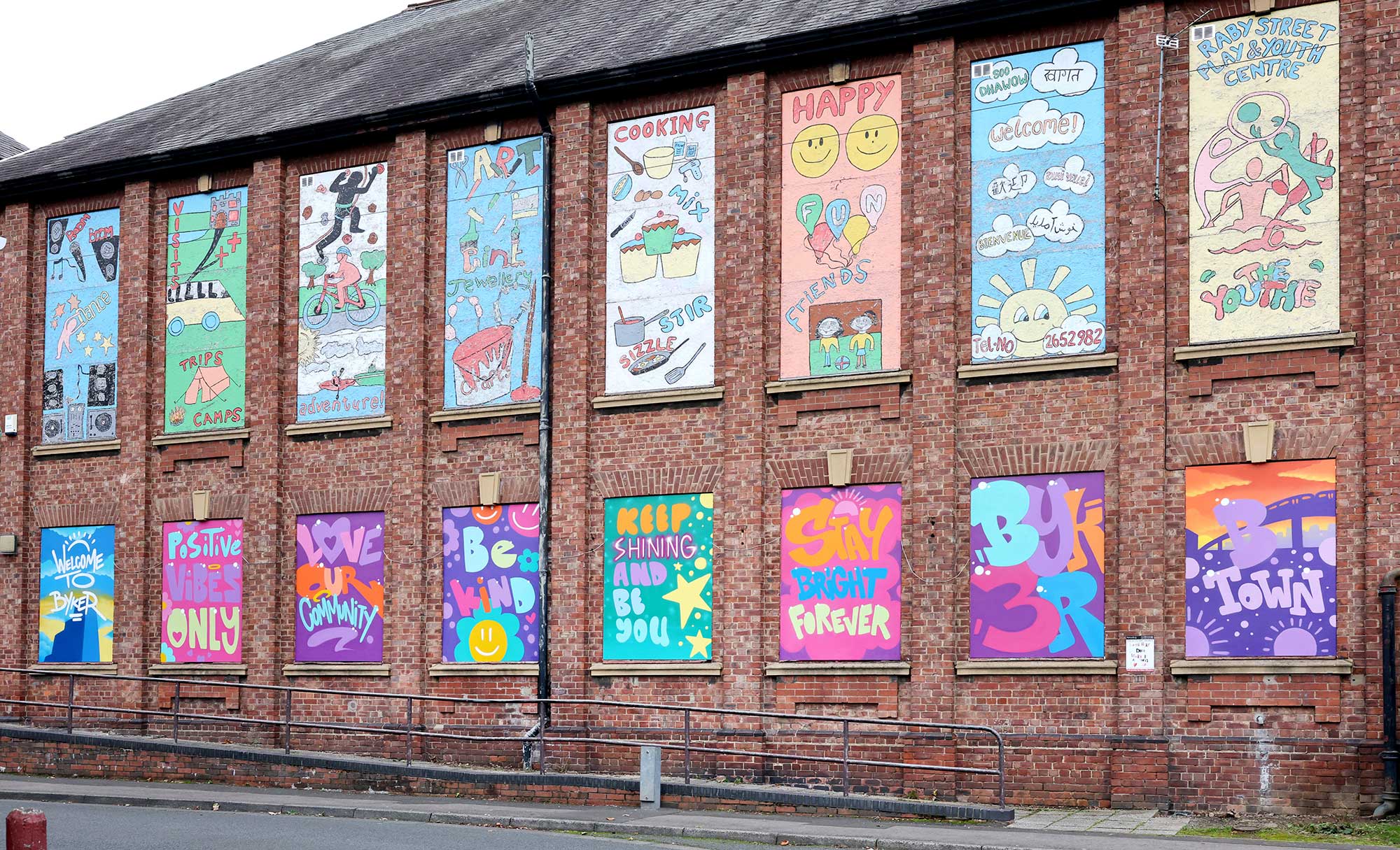 Vibrant pictures are painted on the wall of a tall old building.