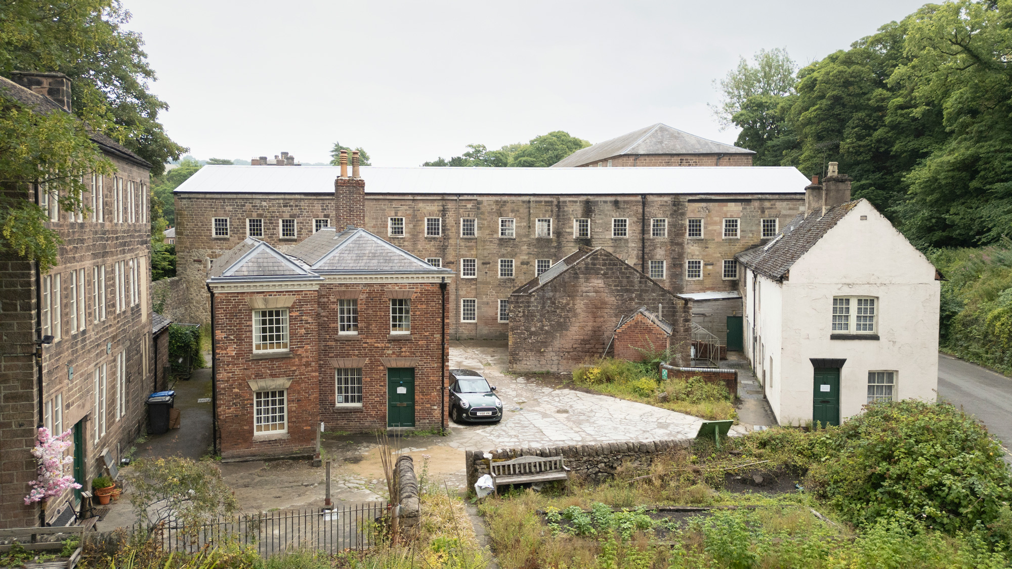 Cromford Mills in Derbyshire, showing stone buildings and cottages at risk of deterioration.