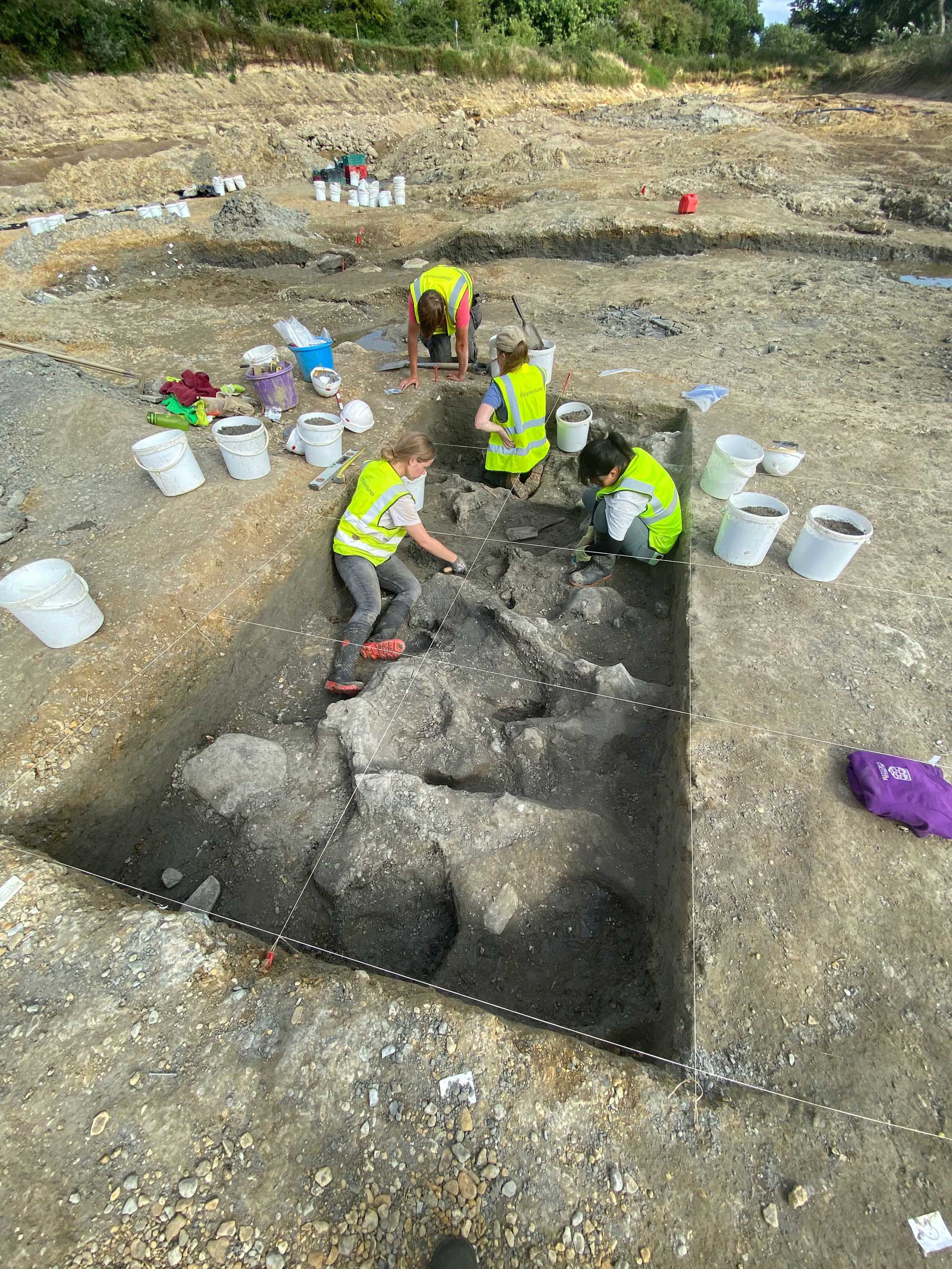 Four archaeologists excavating a trench.