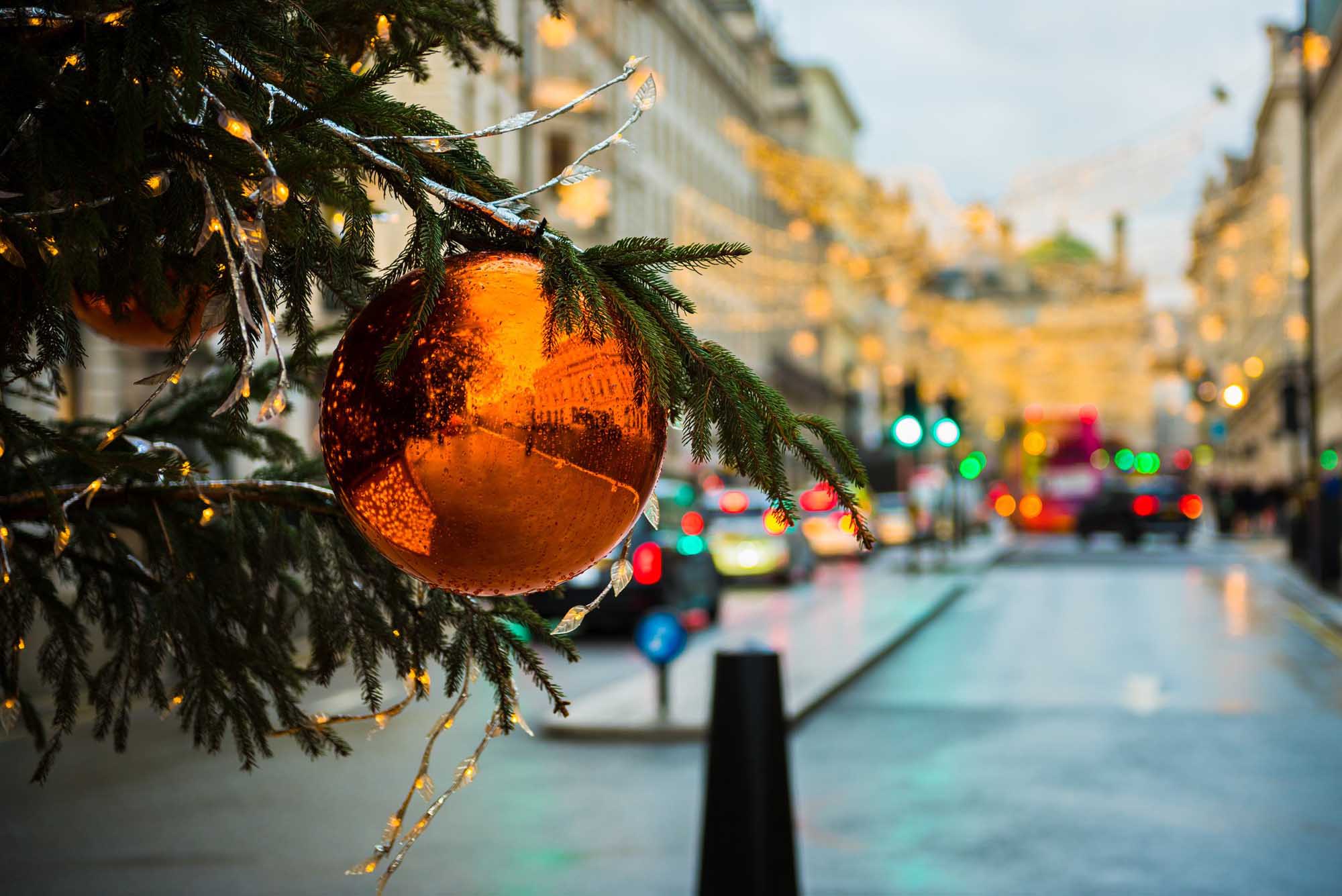 Bauble and branches of a Christmas Tree in foreground on the left, and out of focus London City Street on the right half of the image.