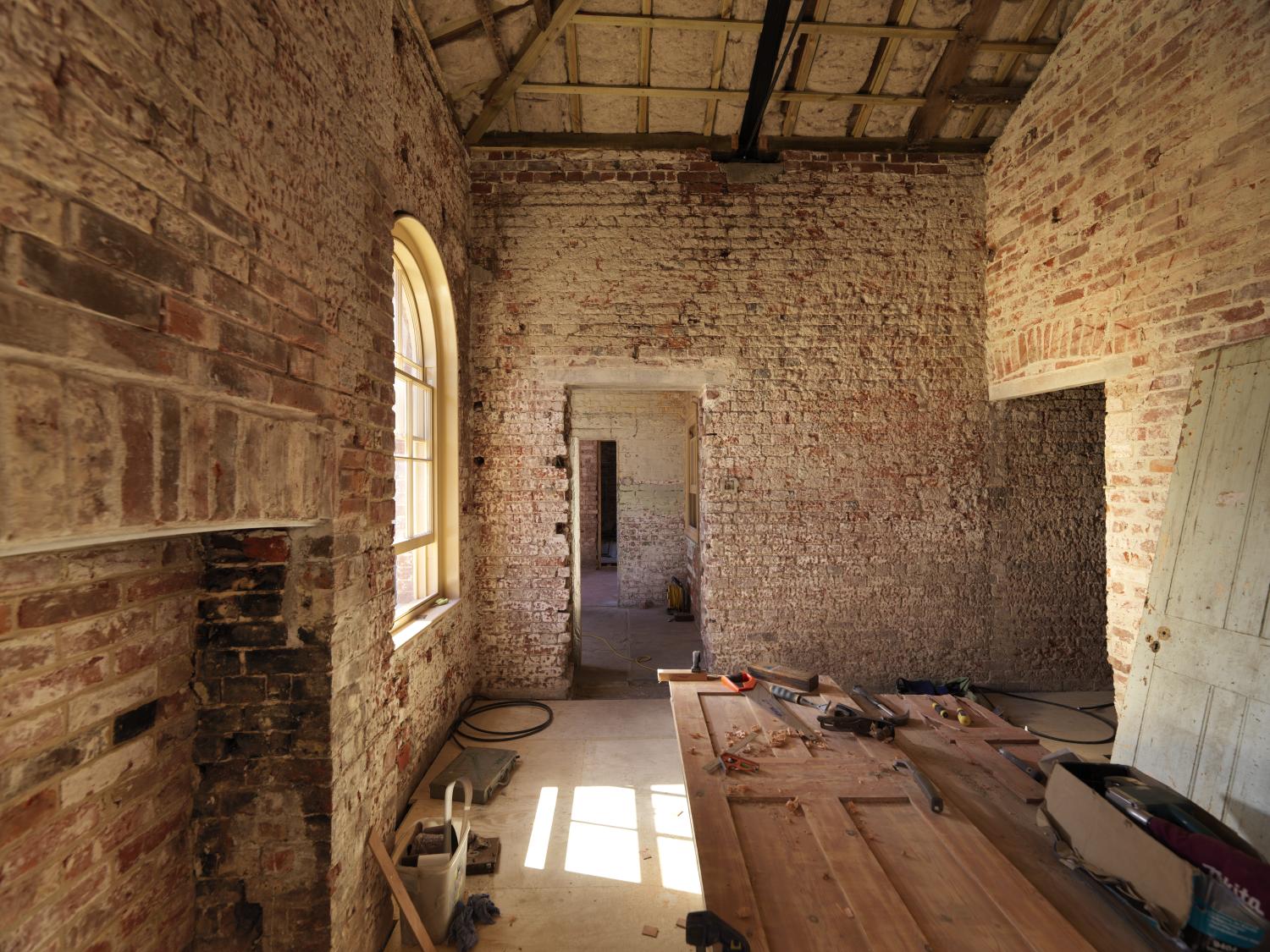 Tools rest on a horizontal door in a red brick room.