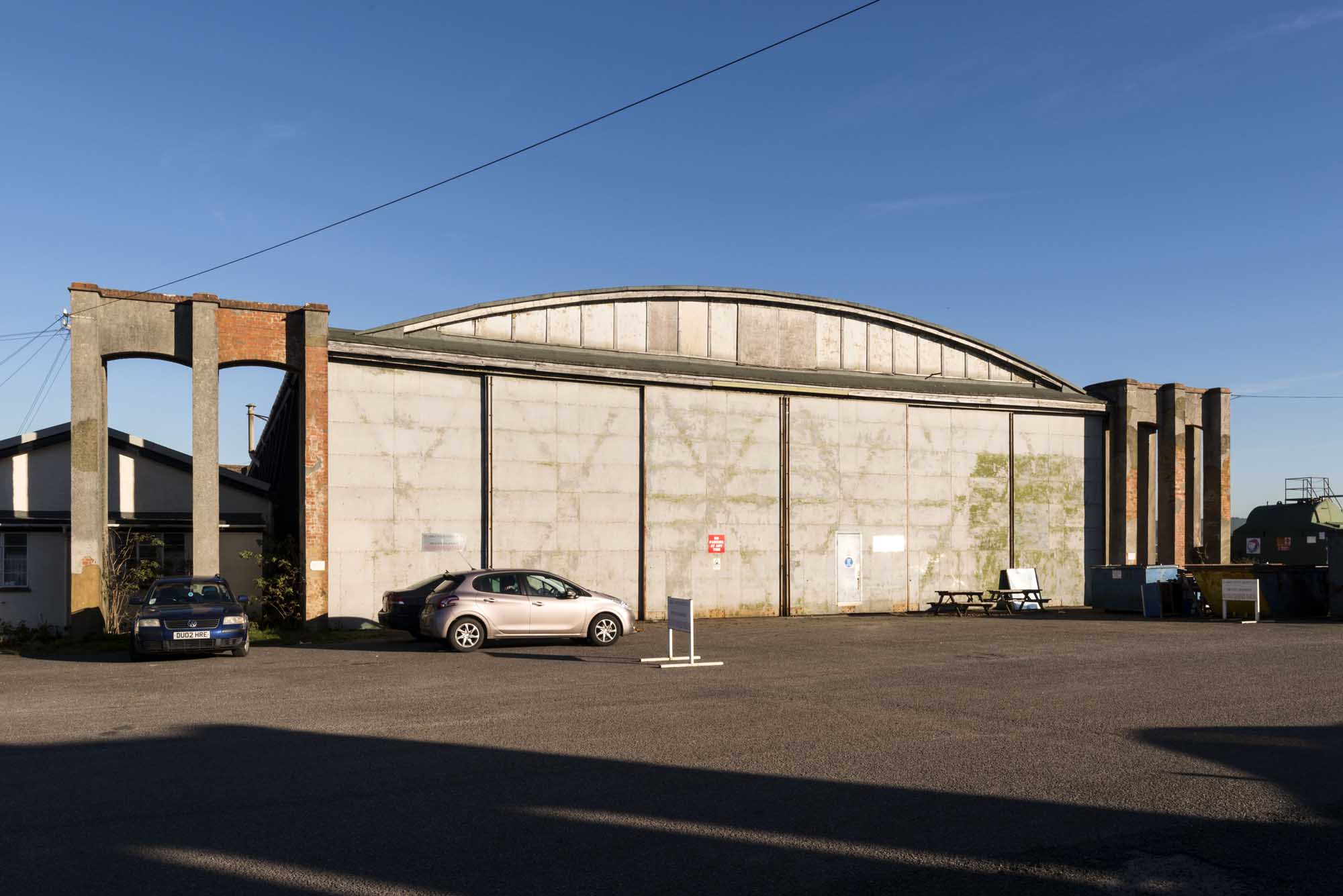 Image of the exterior of a historic aircraft hangar, a large single story building formerly used as an aircraft hangar.