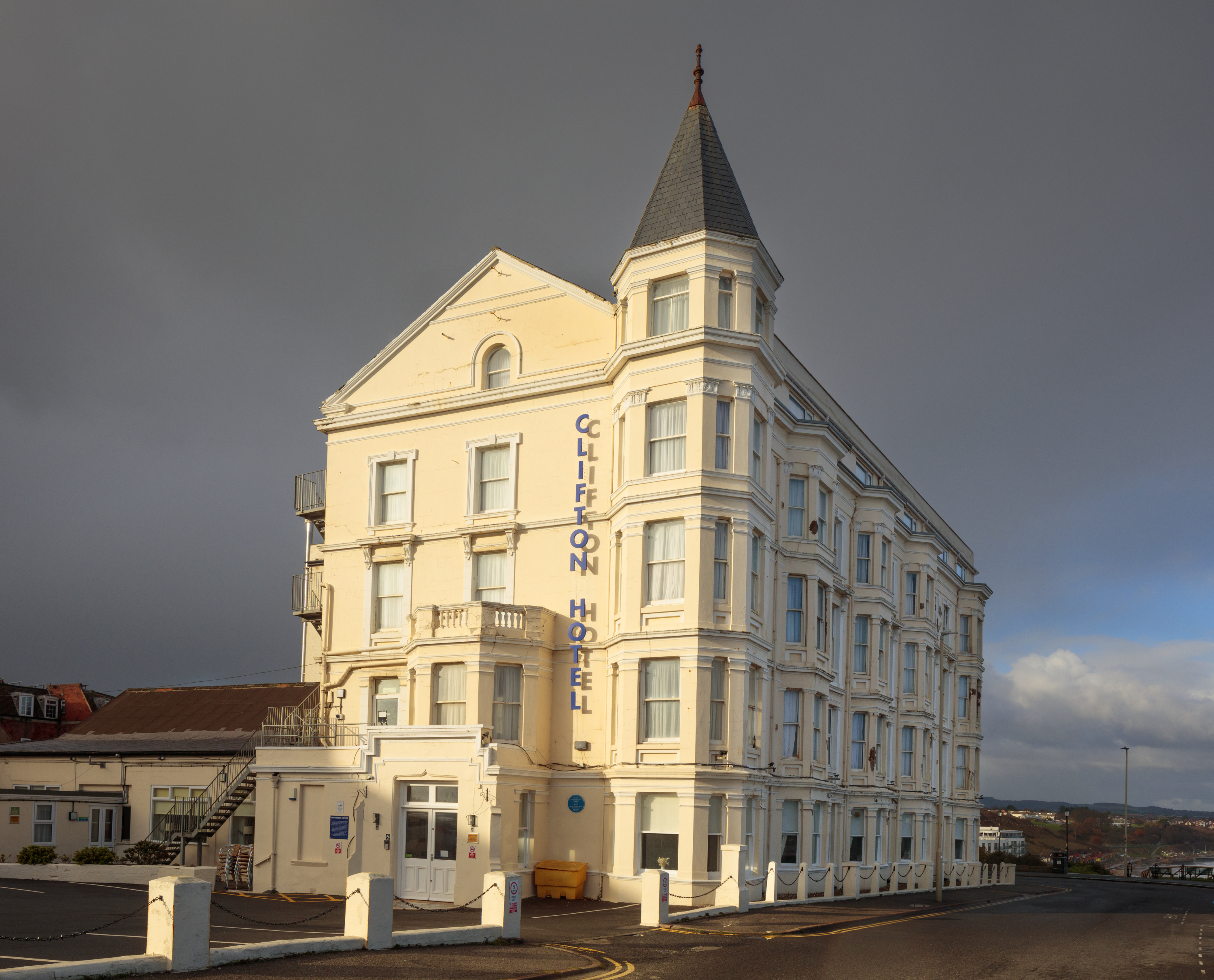 A photograph of a Victorian hotel building with a distinctive corner tower with the hotel's name 'CLIFTON HOTEL' displayed vertically down one side.