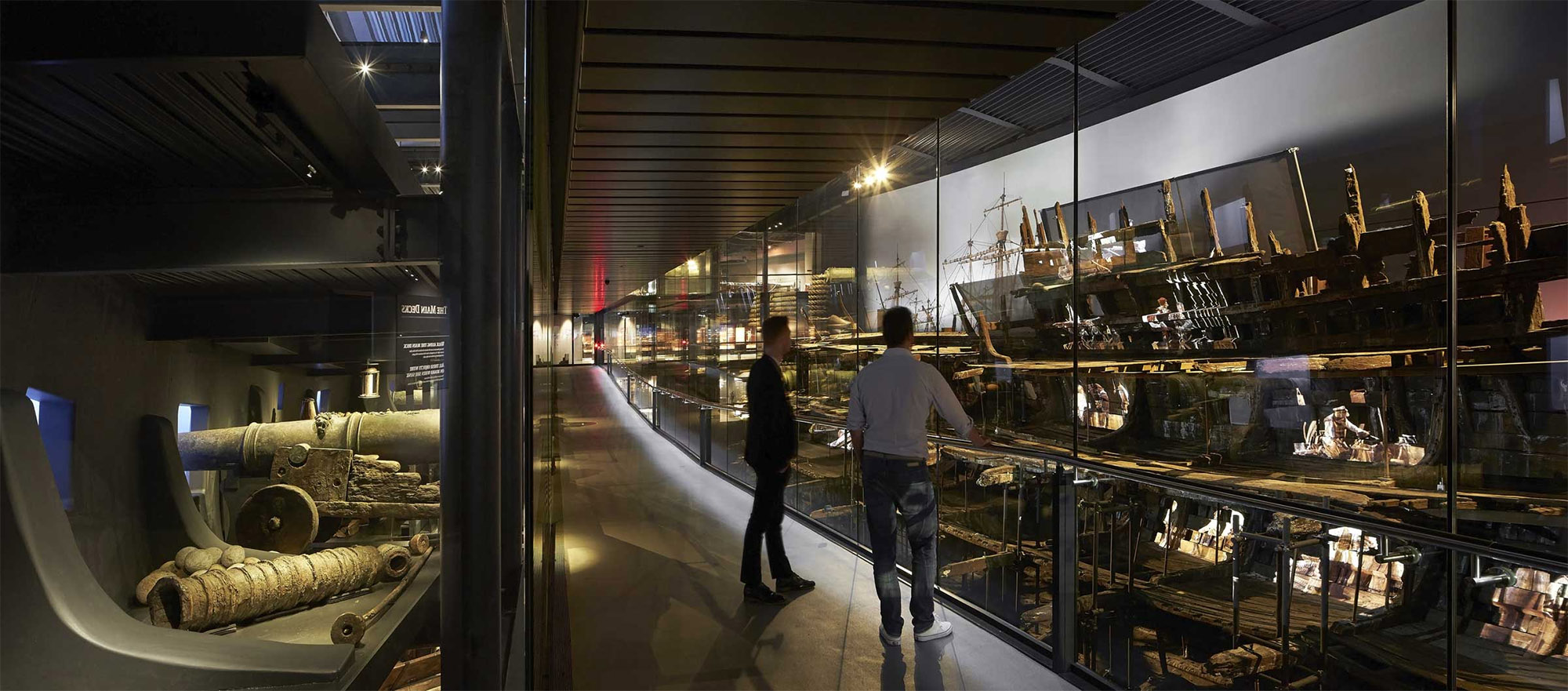 Two people are standing in front of exhibits displayed behind glass.