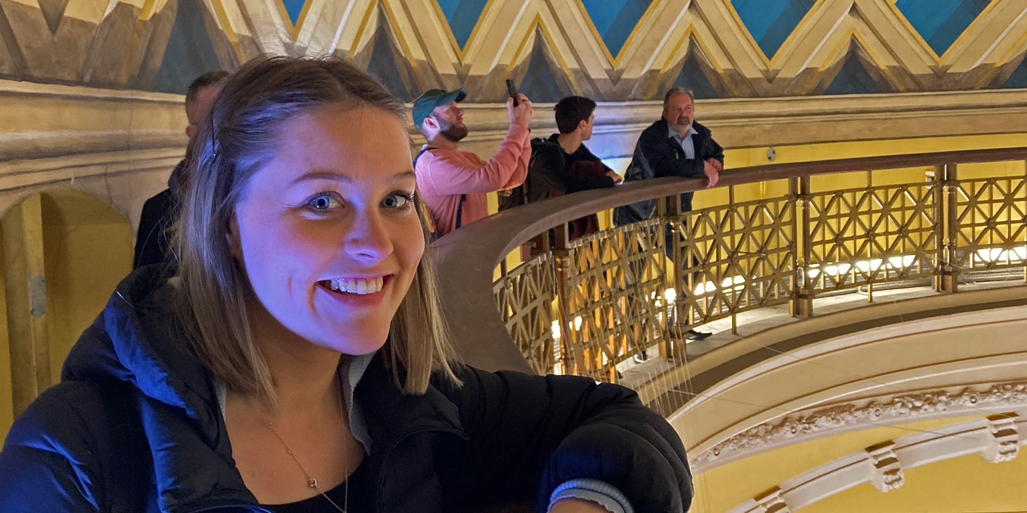 Apprentice Josie Parry smiles at the camera from a historic viewing gallery