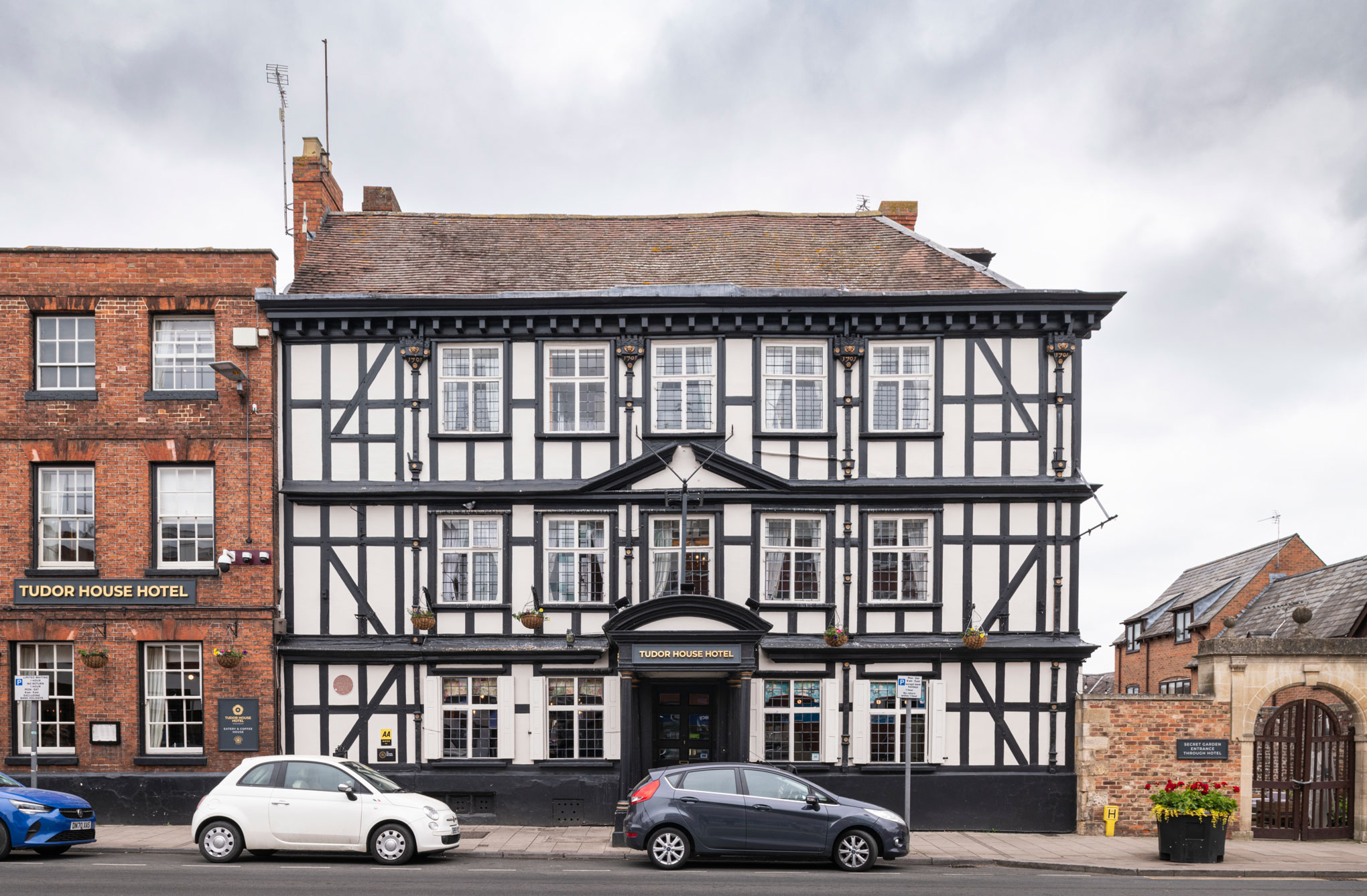 A three storey timber-framed hotel building with a brick extension, in a historic high street setting.