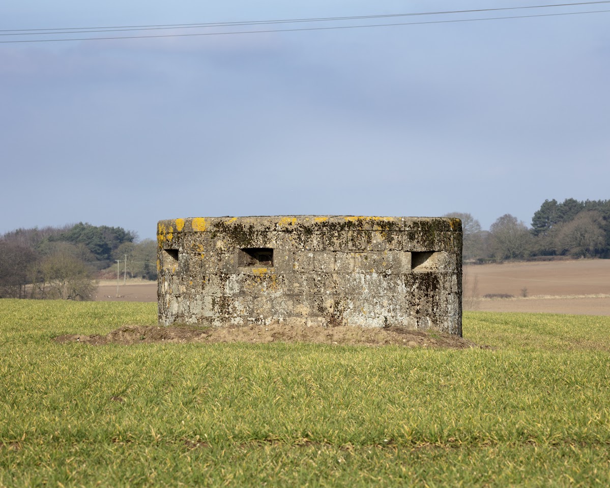 A circular concrete structure with narrow slots, in a field