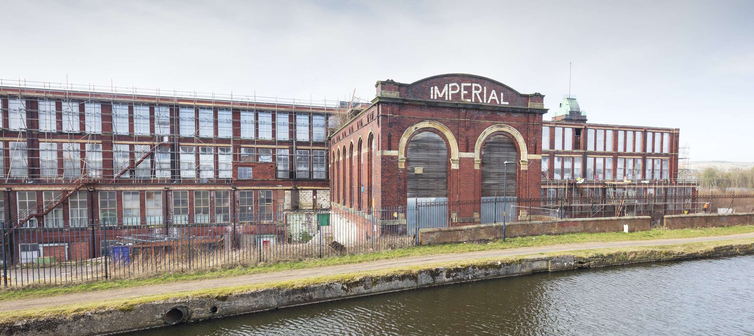 A large brick building next to a water course.