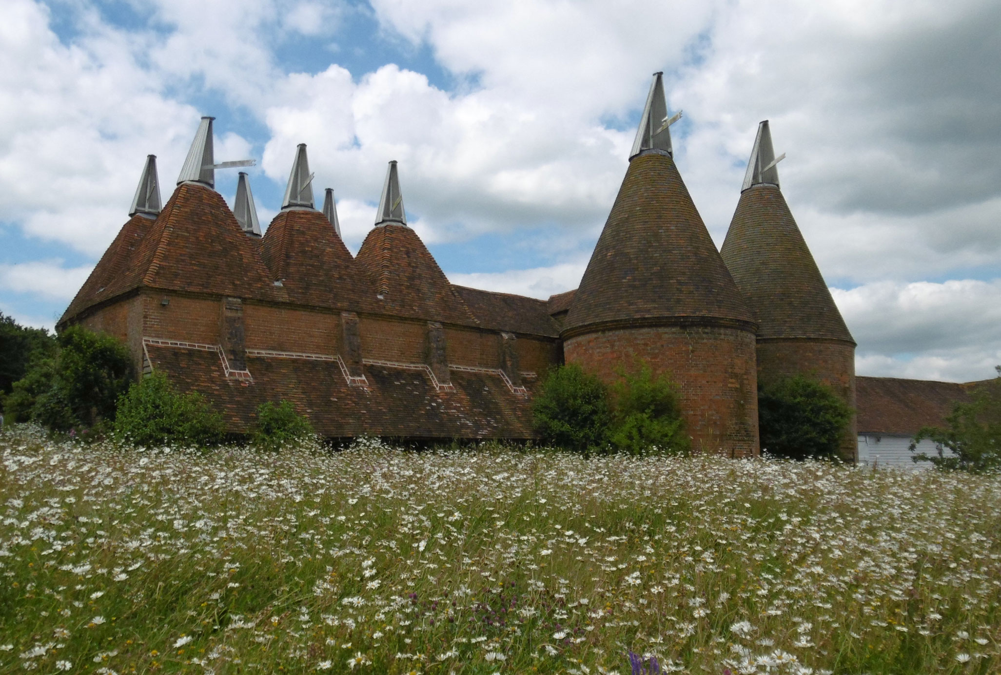 A large brick built oasthouse with white cowls.