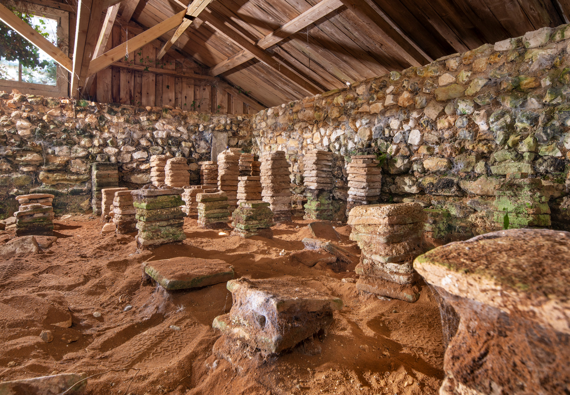 Stones stacked in columns against a low stone wall and wooden shelter.