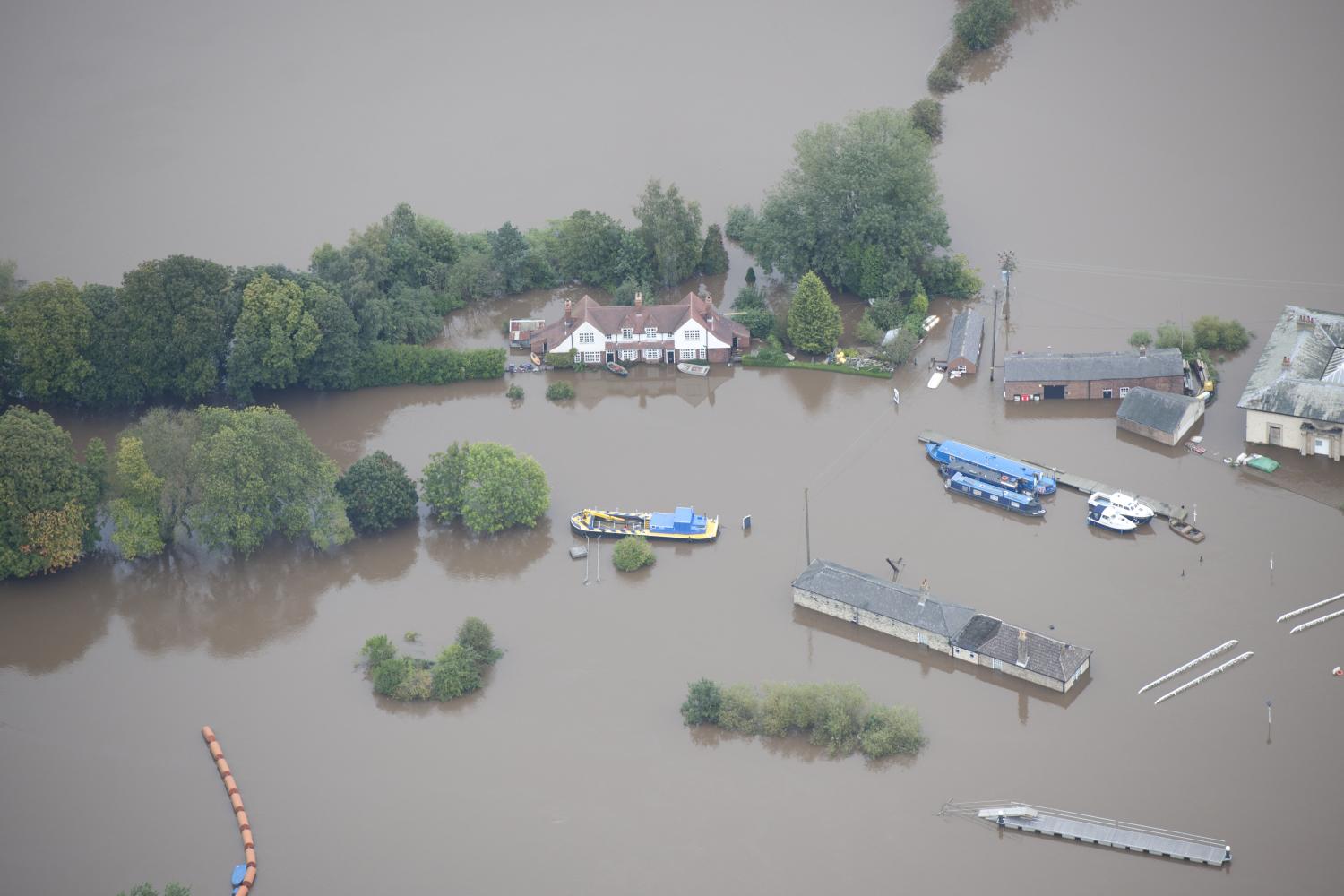 Aerial view showing several buildings submerged in floodwater.