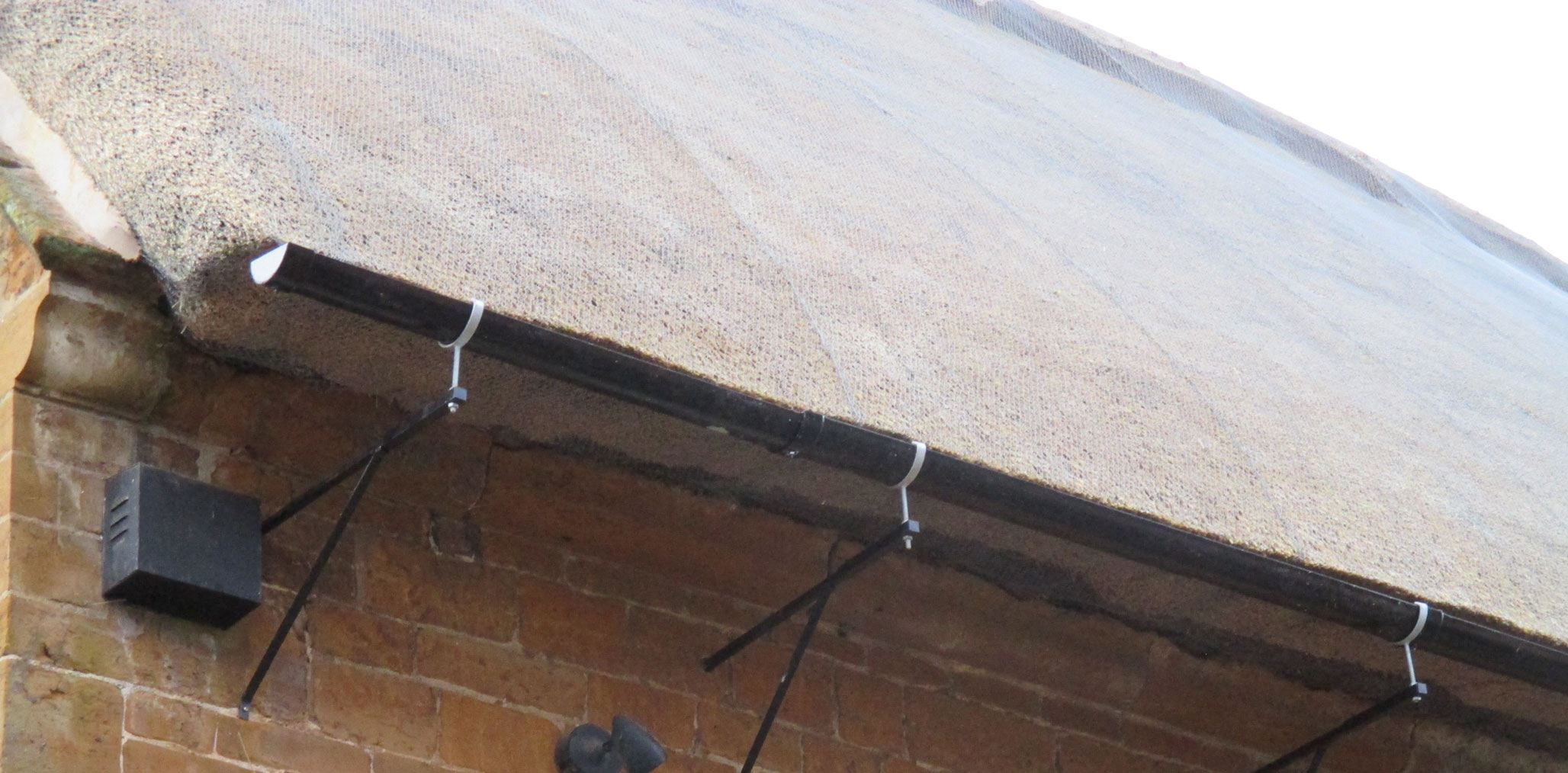 Detail of a gutter bracket below the eaves of a thatched public house.