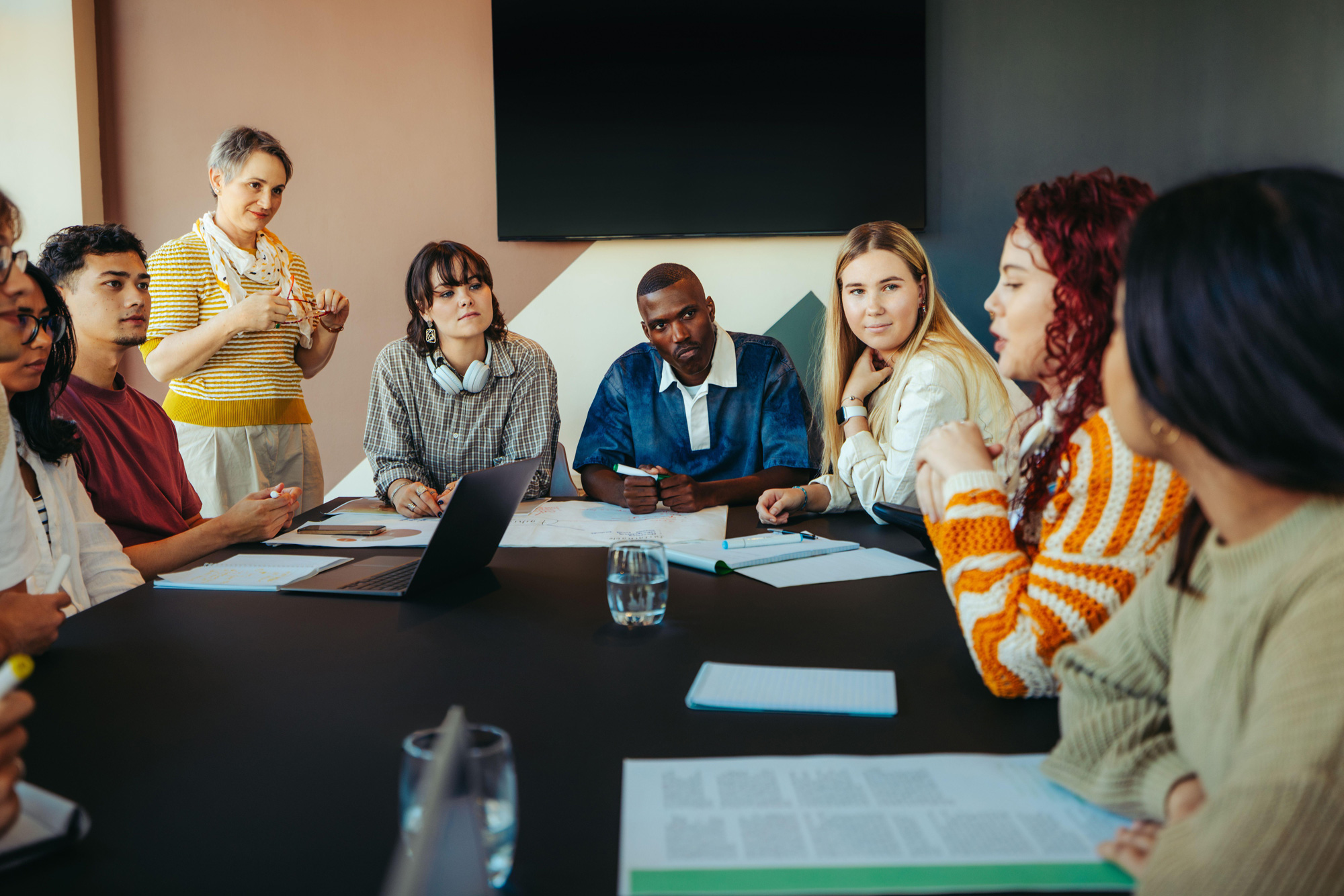 Diverse group of young adults actively participating in a learning discussion around a table.
