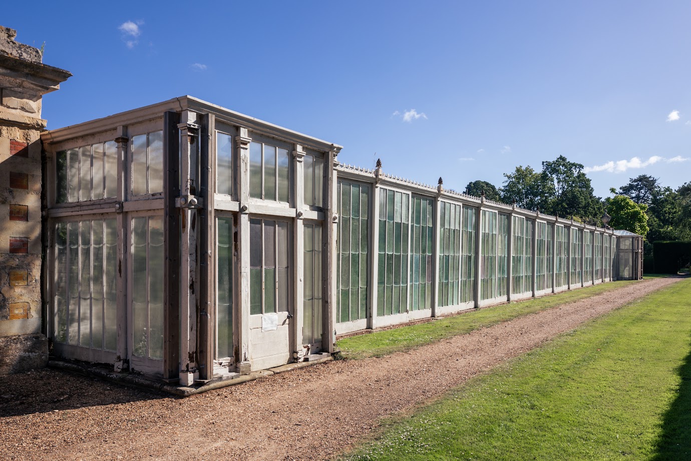 A long rectangular building with glass panels, white wooden surround and small decoration.