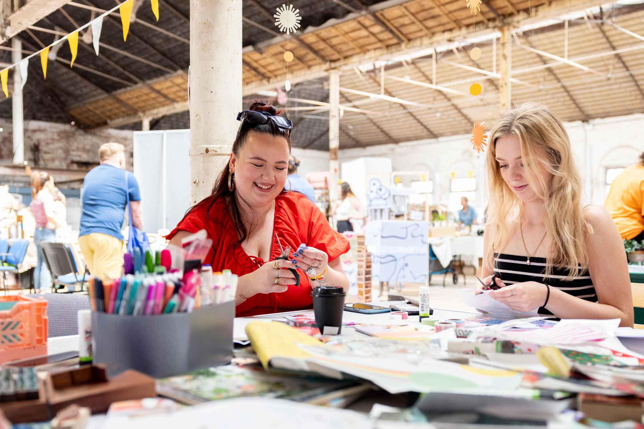 Participants at a wellbeing festival engaged in crafting, within a historic mill building.