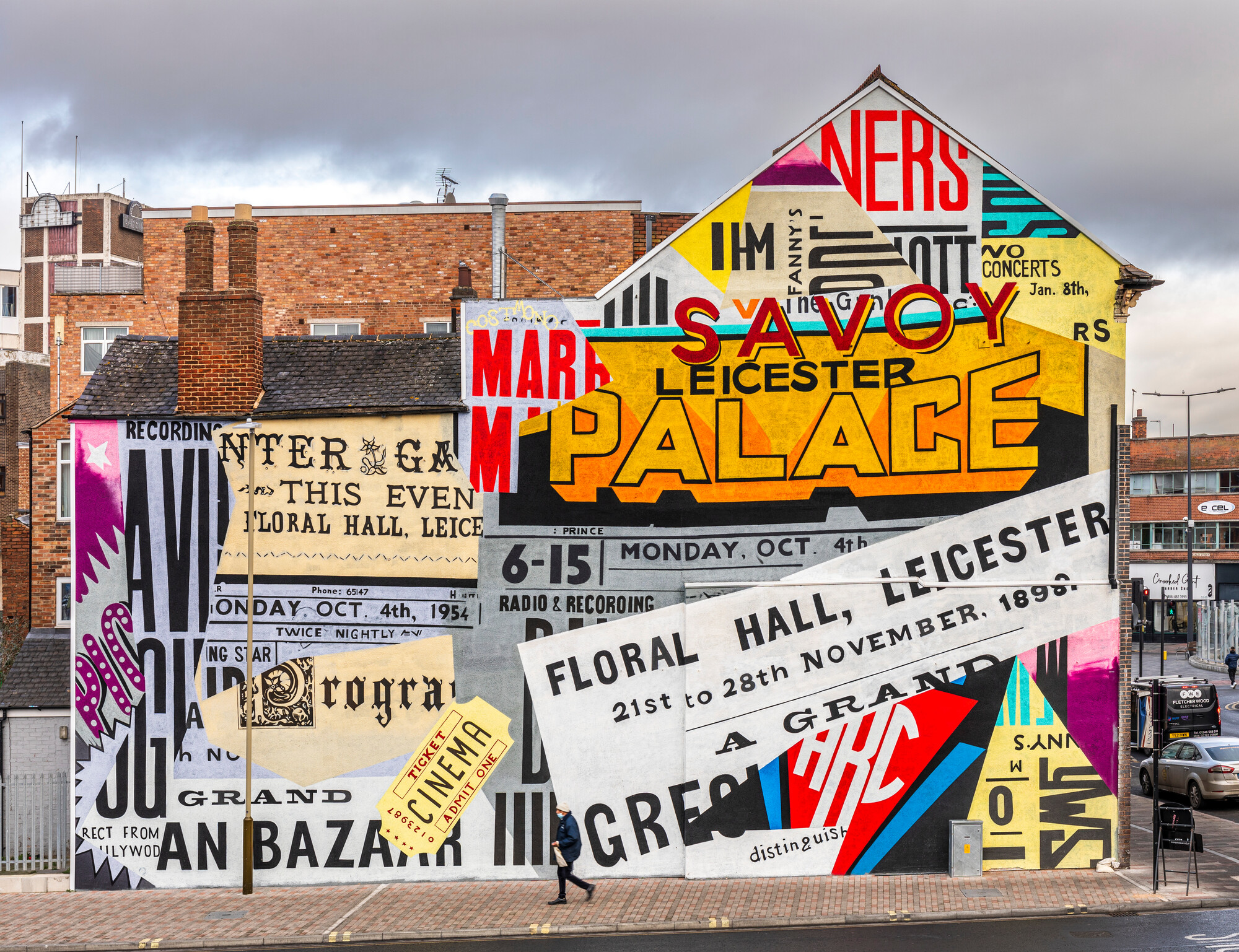 Exterior view of the south side of a building at the junction of Savoy Street and Belgrave Gate, with a mural celebrating entertainment venues which formerly stood nearby.